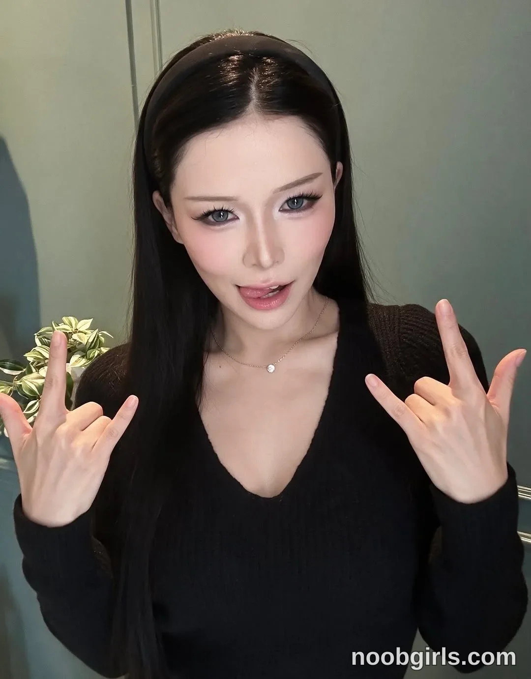 Bae Bae Facing the camera with both hands raised wearing Black long-sleeved V-neck knit top in room