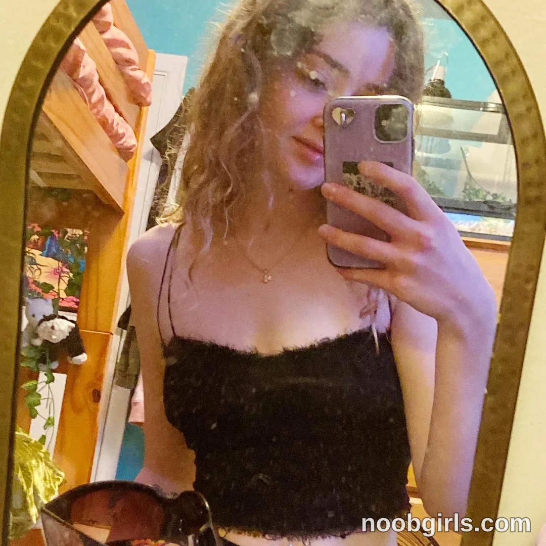 Britt taking a mirror selfie wearing black fuzzy crop top in bedroom