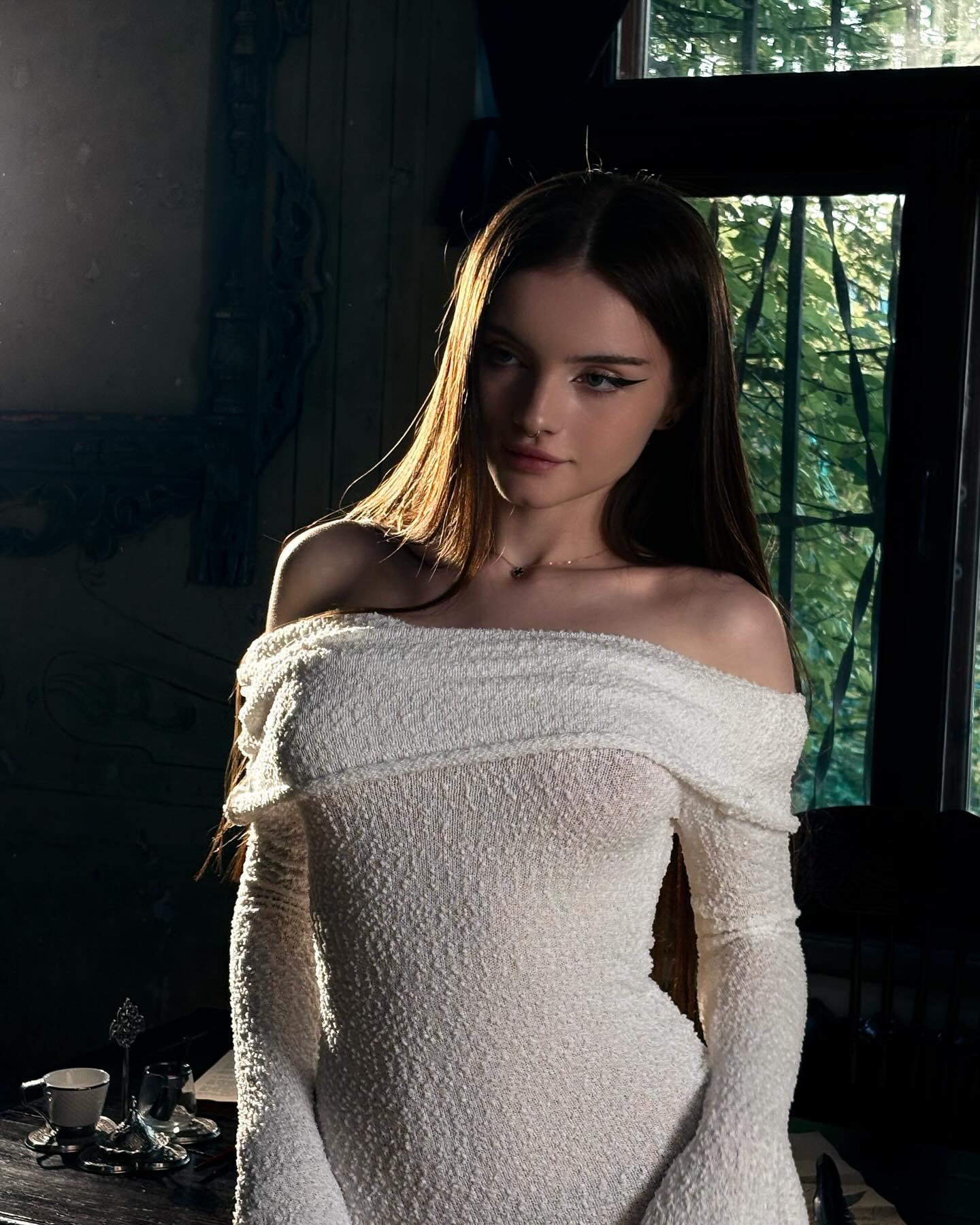 bellacle wearing white off-shoulder dress in room near window