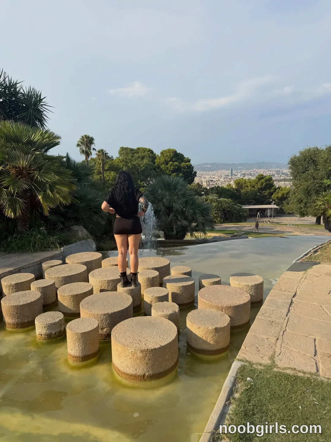 bexbex945874 standing on stone pedestals in water wearing black t-shirt in park fountain overlook at Barcelona