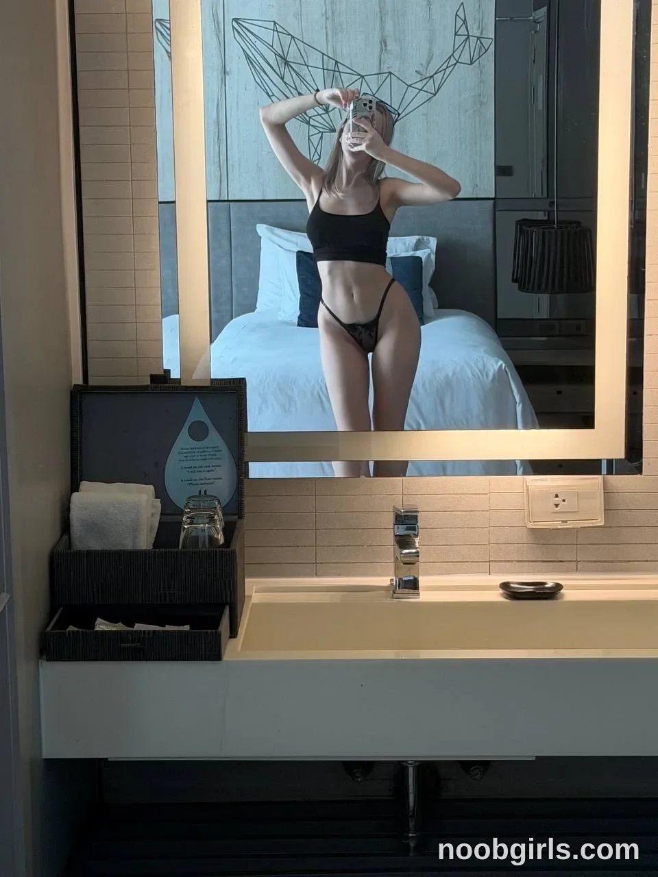 boobybliss taking a mirror selfie wearing black crop top in hotel bathroom