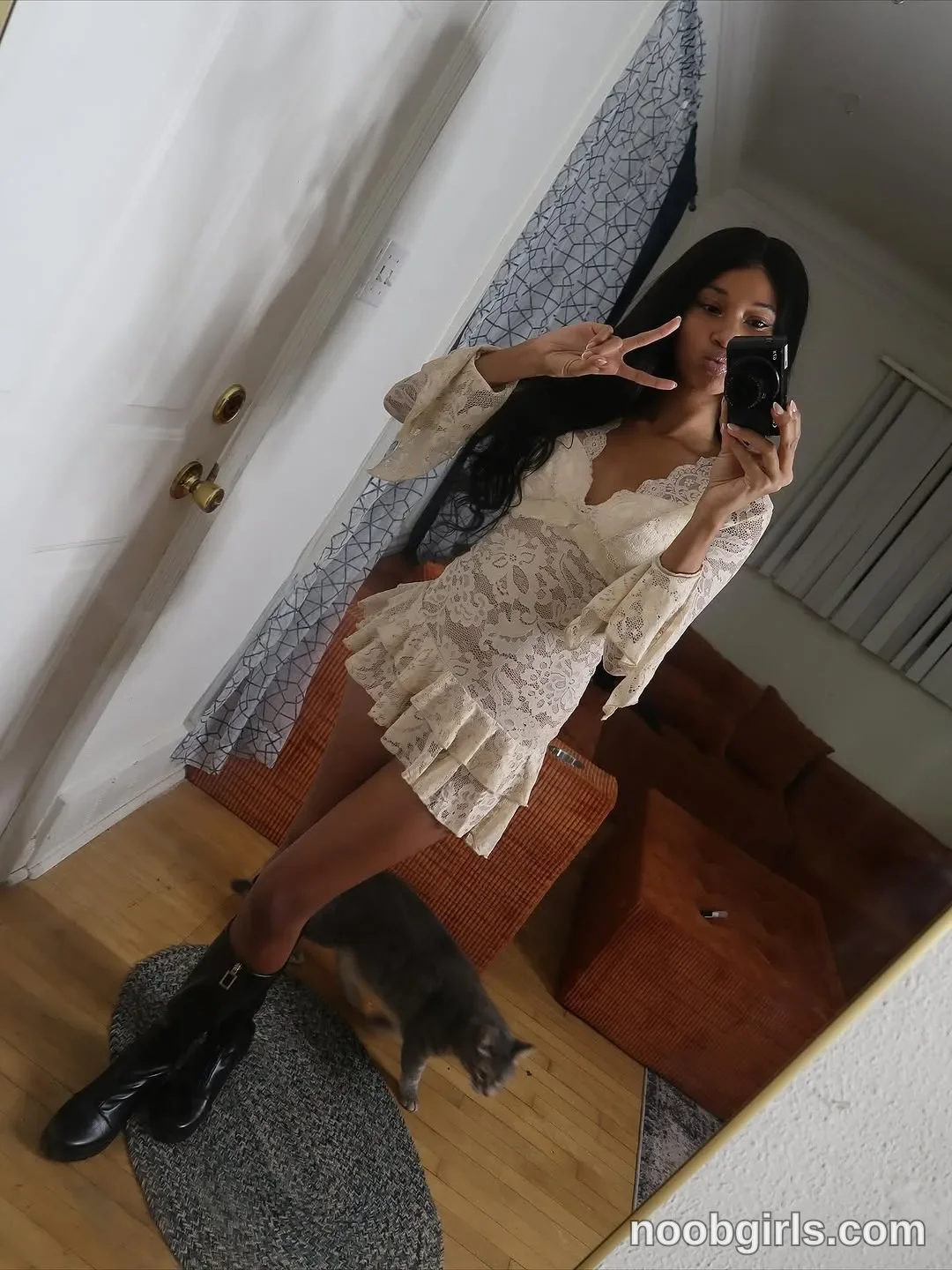 Cedaya taking a mirror selfie with a camera wearing off-white lace mini dress with flared long sleeves and ruffled hem