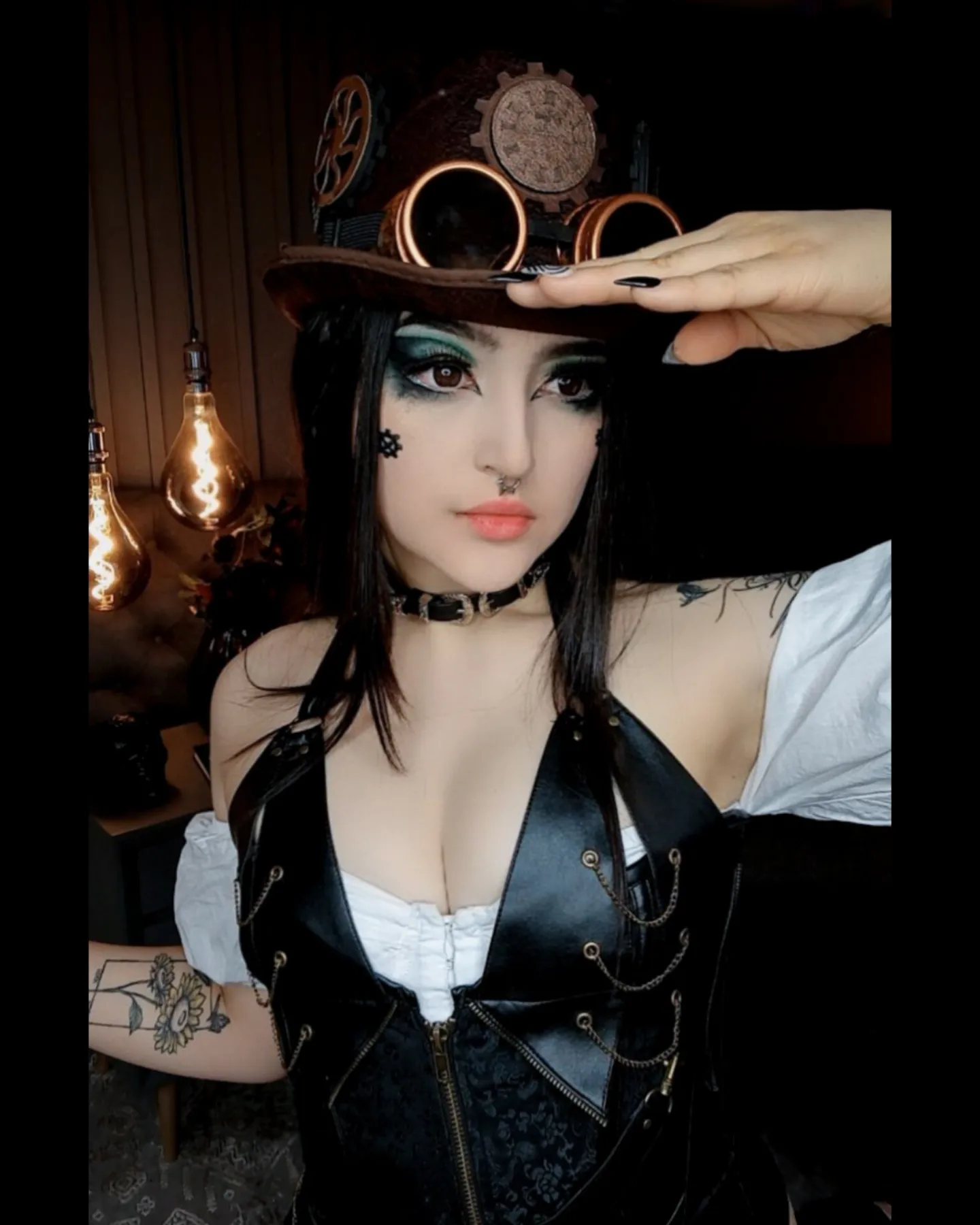 charlotte_germanotta_ posing with hand to hat wearing brown steampunk hat with goggles in room
