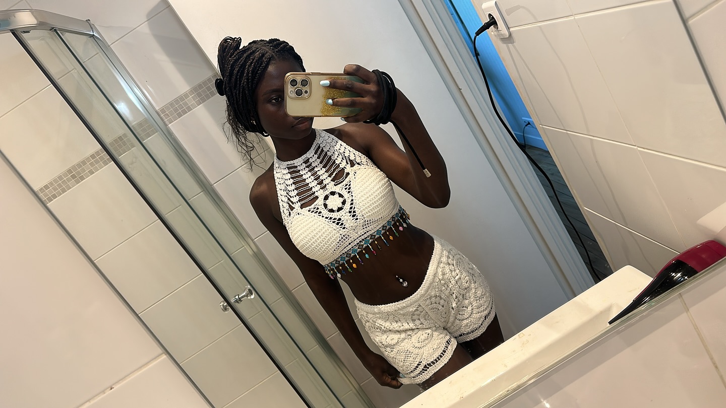 conymegan taking a mirror selfie wearing white crochet crop top in bathroom