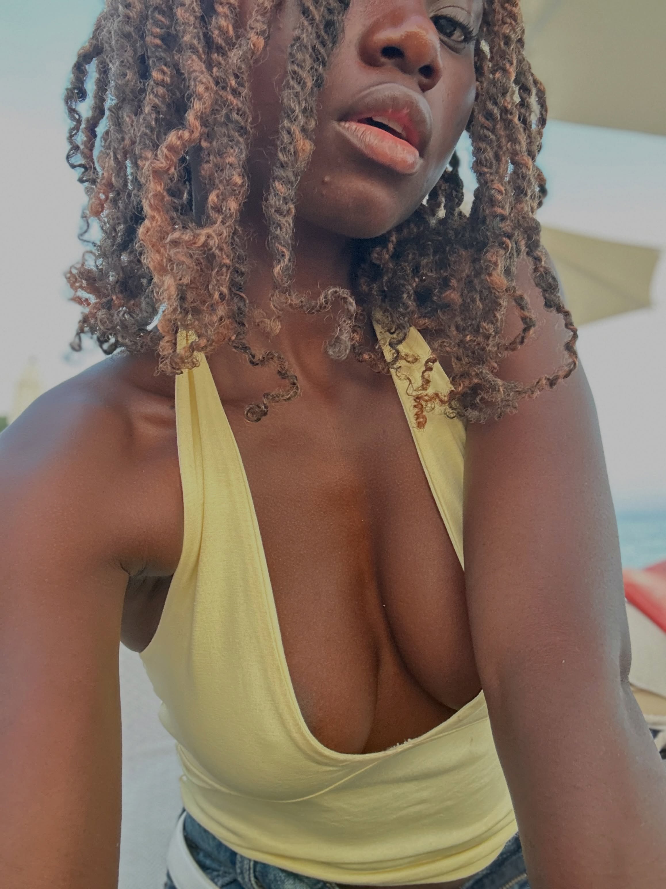 conymegan posing for a selfie wearing yellow halter top in beach