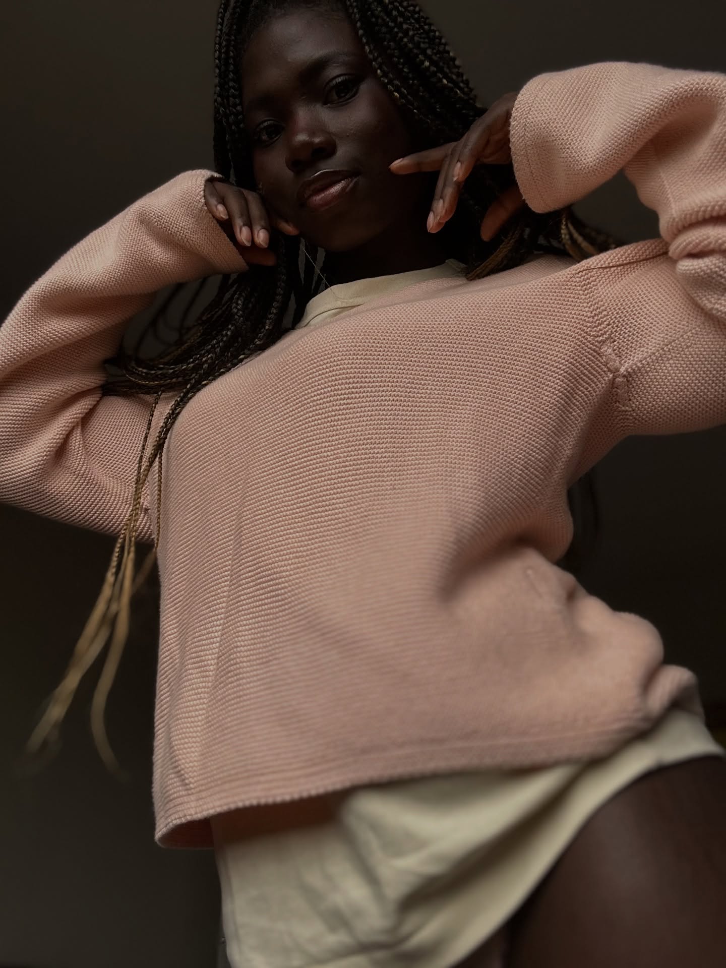 conymegan posing with hands near face wearing pink knit sweater