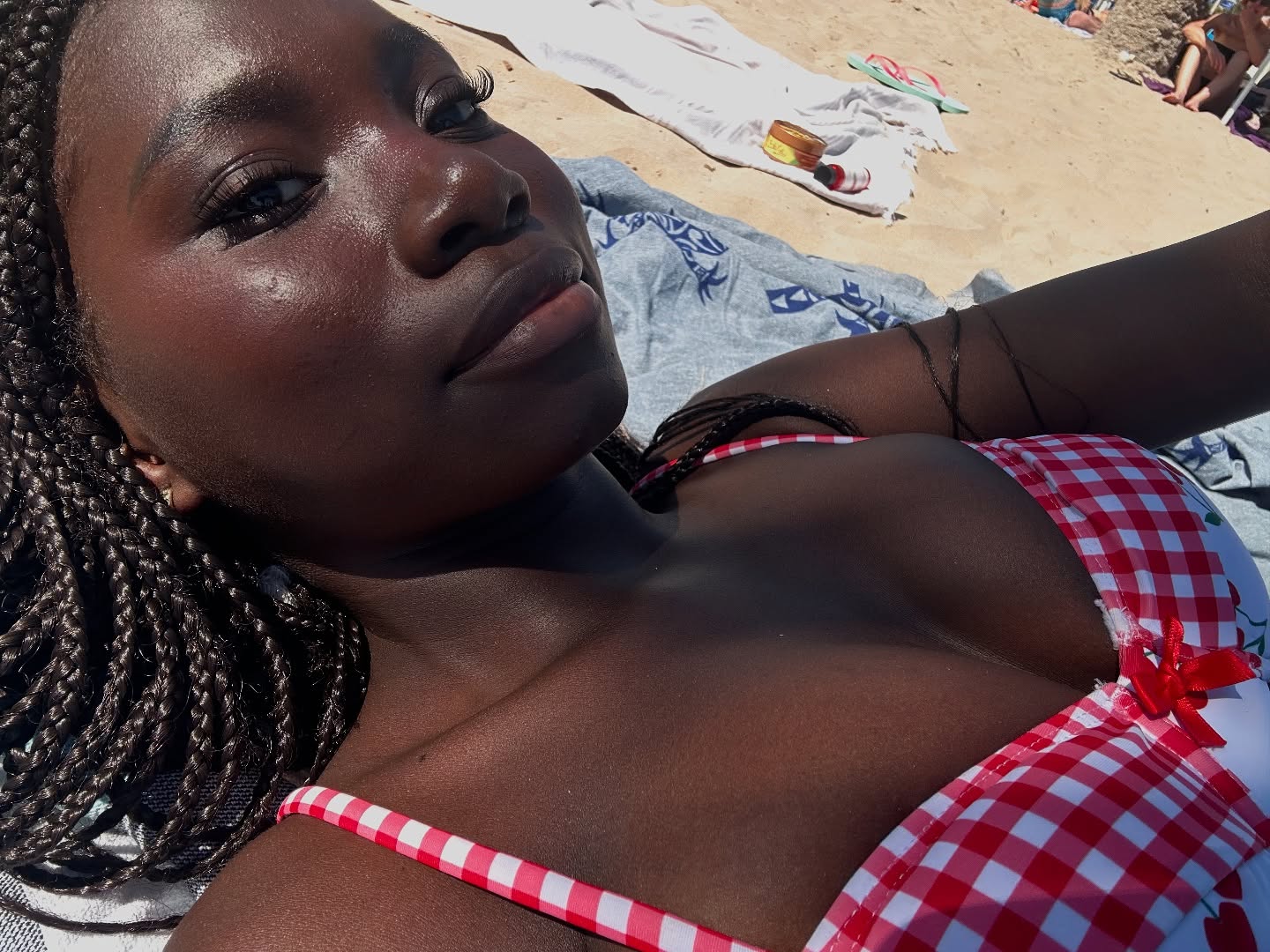 conymegan sunbathing wearing red and white gingham bikini top in sandy beach