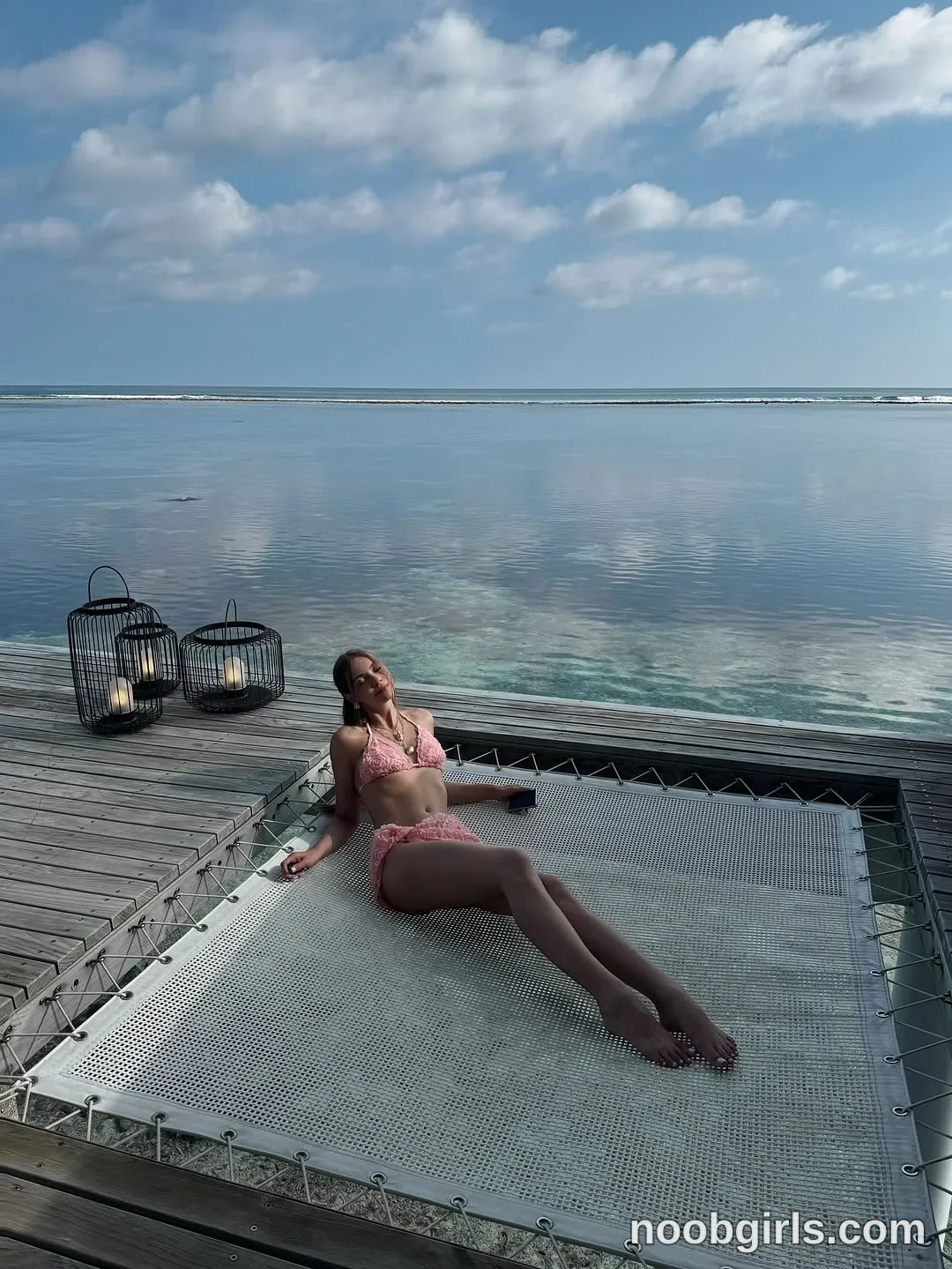 CoverM Reclining on the mesh platform wearing Pink patterned bikini top in wooden deck above seawater in Maldives