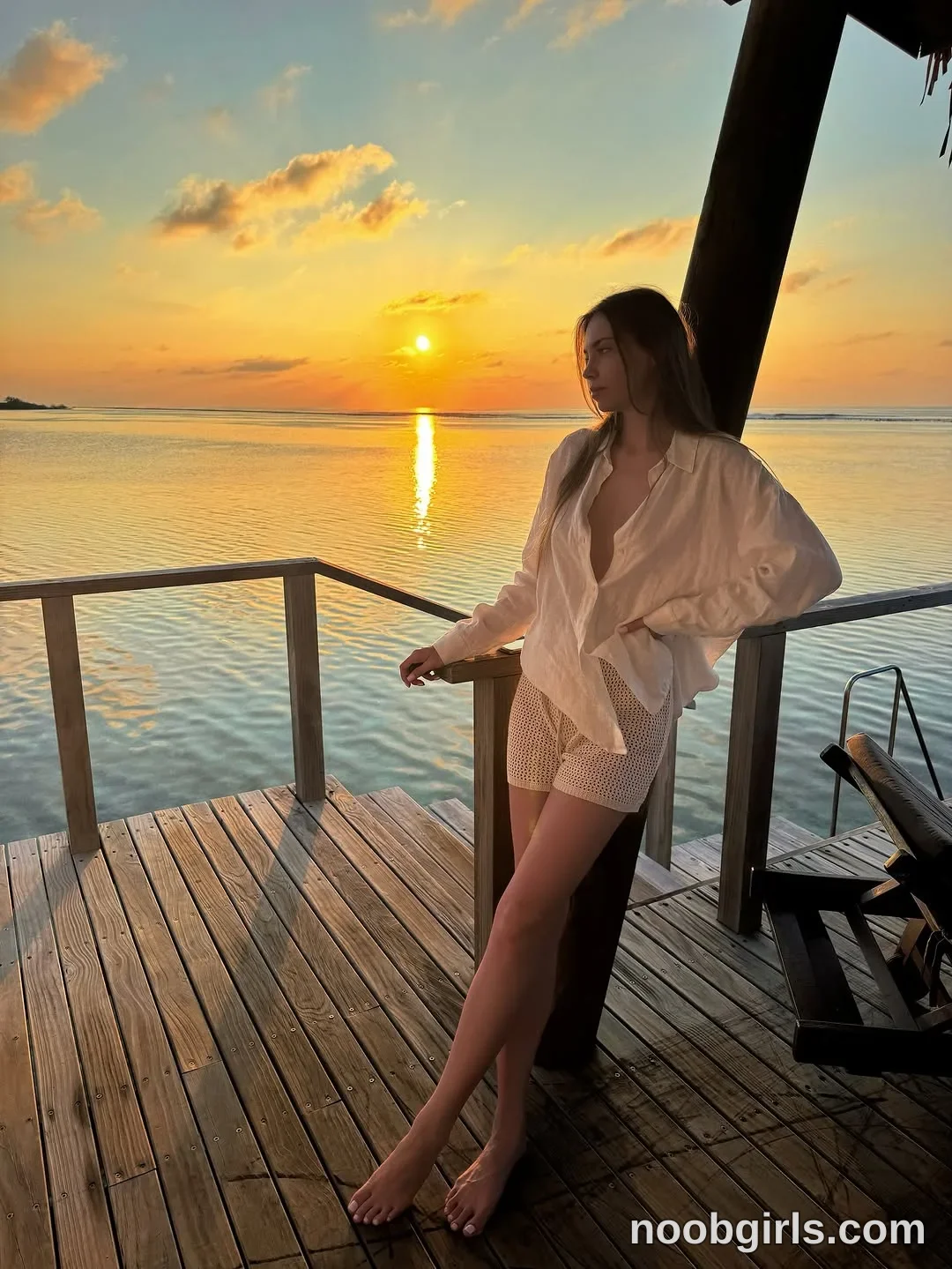 CoverM Standing barefoot with her legs crossed wearing Loose off-white long-sleeved button-front shirt with an open neckline