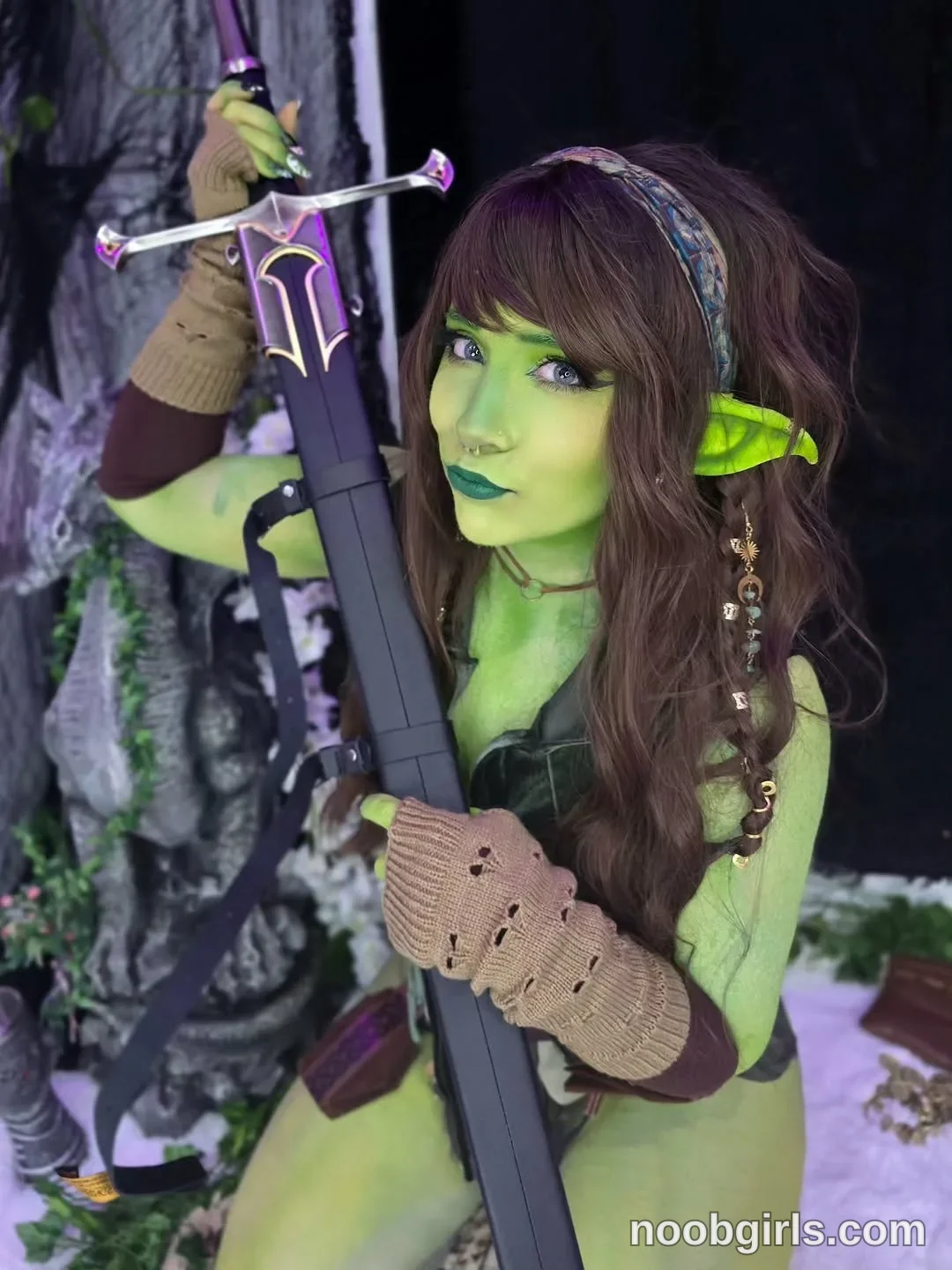 Crimson Kitten Holding the sword hilt above her head with one hand wearing Dark green sleeveless top in staged area