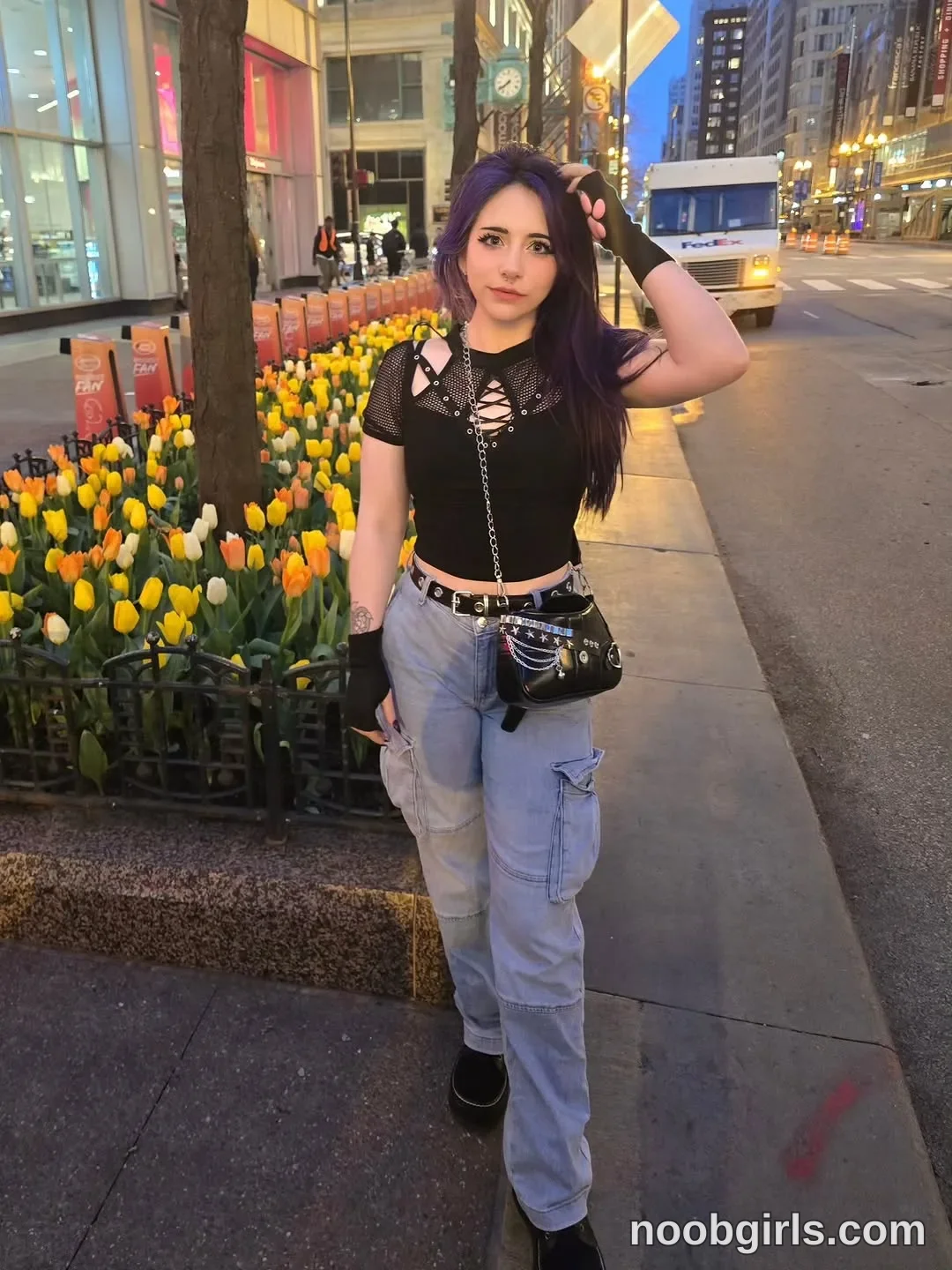 Crimson Kitten Standing on the sidewalk with one hand touching her hair