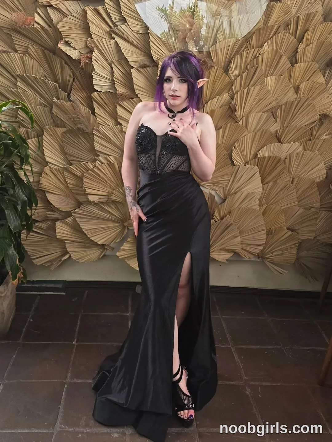 Crimson Kitten Standing with one hand raised near her upper chest
