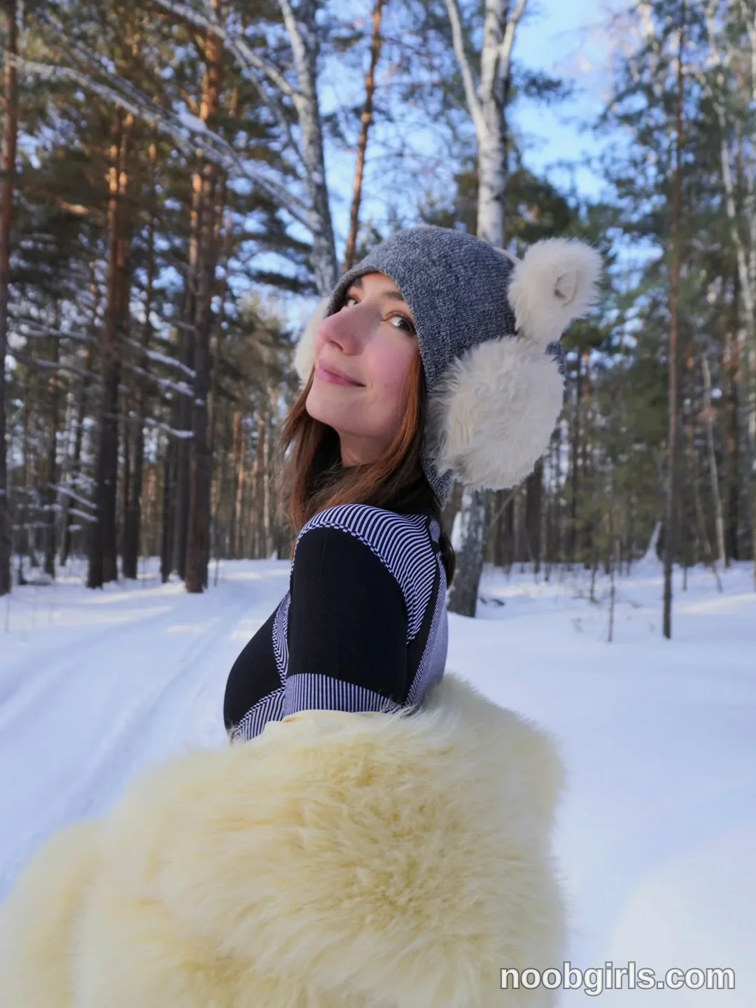 crystalnut looking over shoulder wearing grey knit hat with white pom-poms in snowy forest