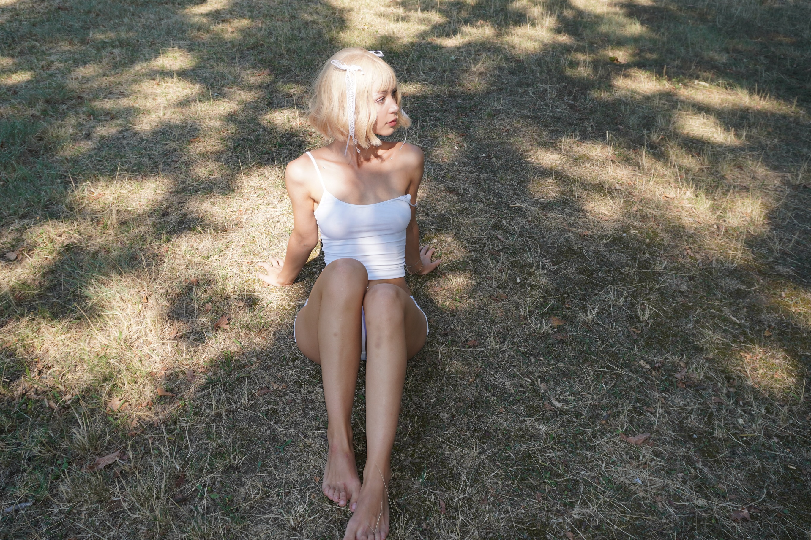 cutieeeeva sitting on the grass wearing white tank top in grassy field