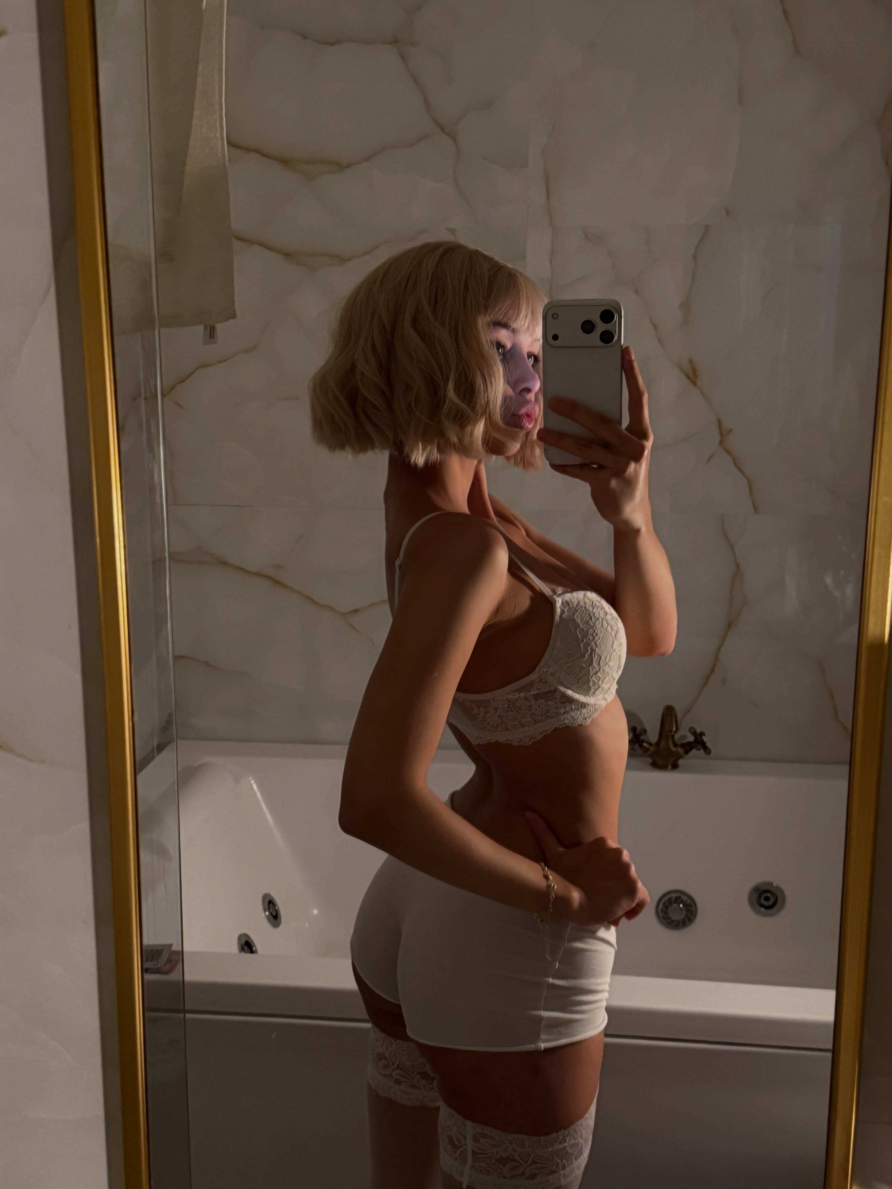cutieeeeva taking a mirror selfie wearing white lace bra in bathroom
