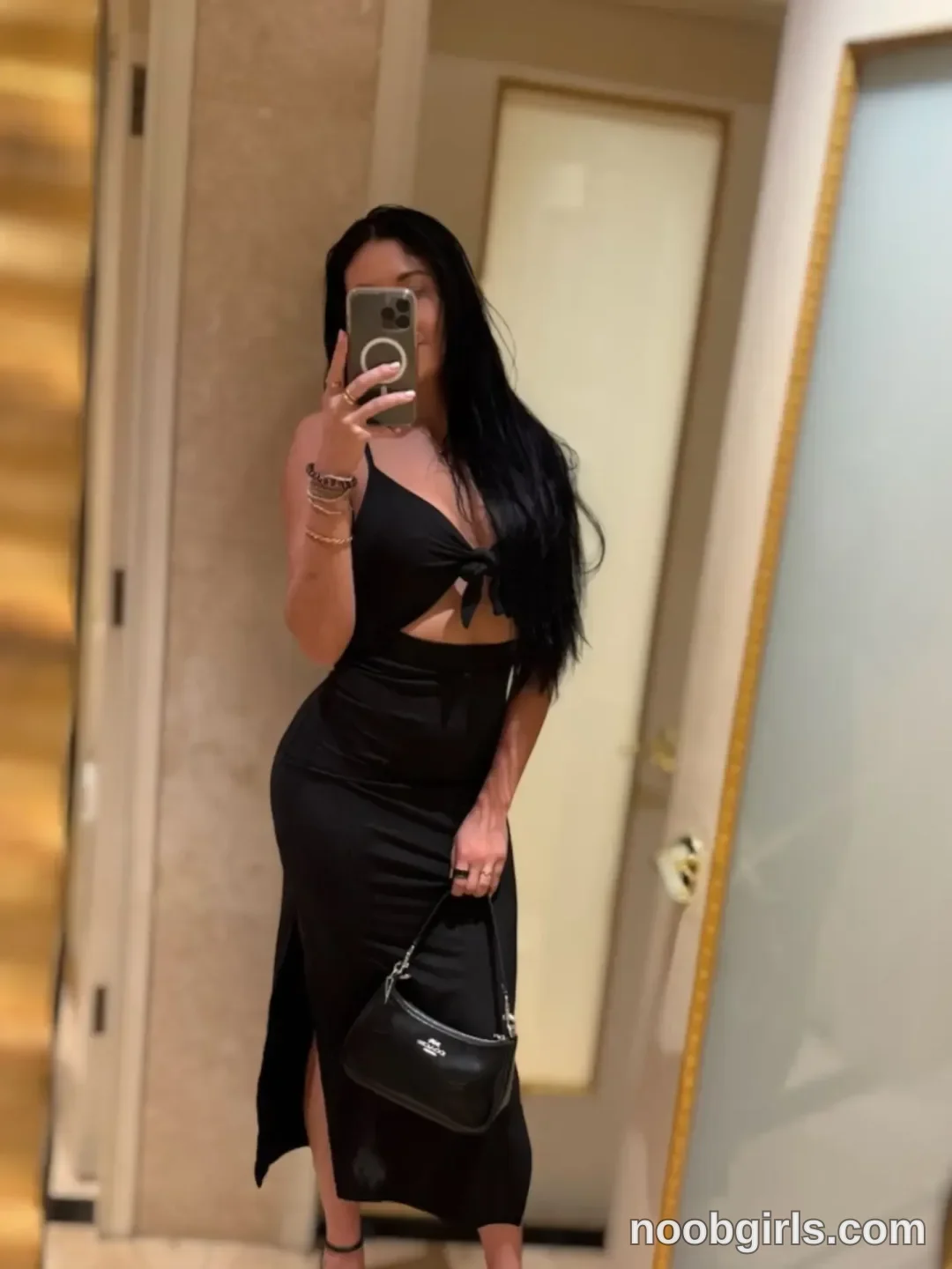 Dazey taking a mirror selfie wearing black cutout dress in hallway