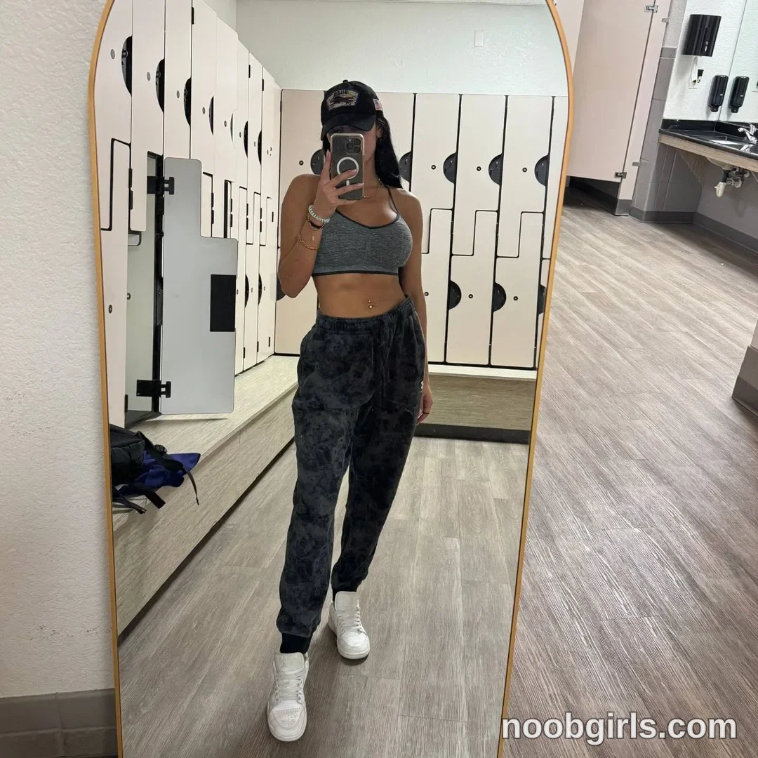 Dazey taking a mirror selfie wearing grey sports bra in locker room