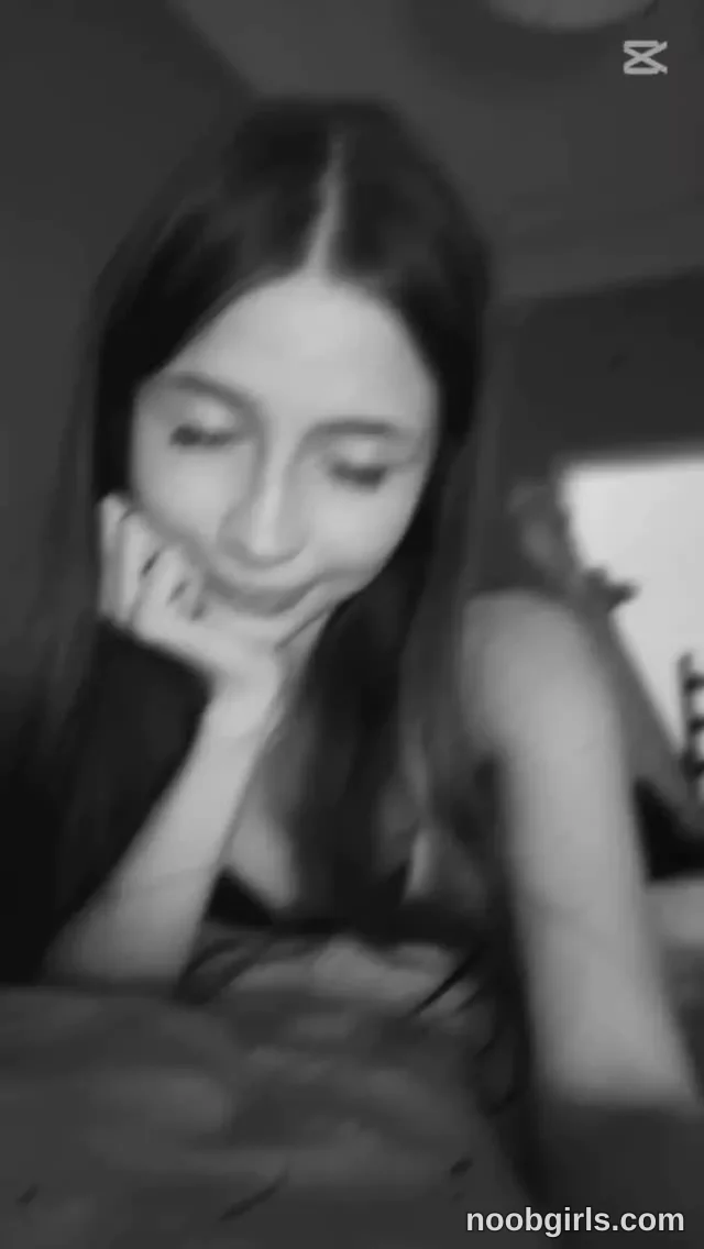 DELORA Resting her cheek on one hand wearing black sleeveless top in bedroom