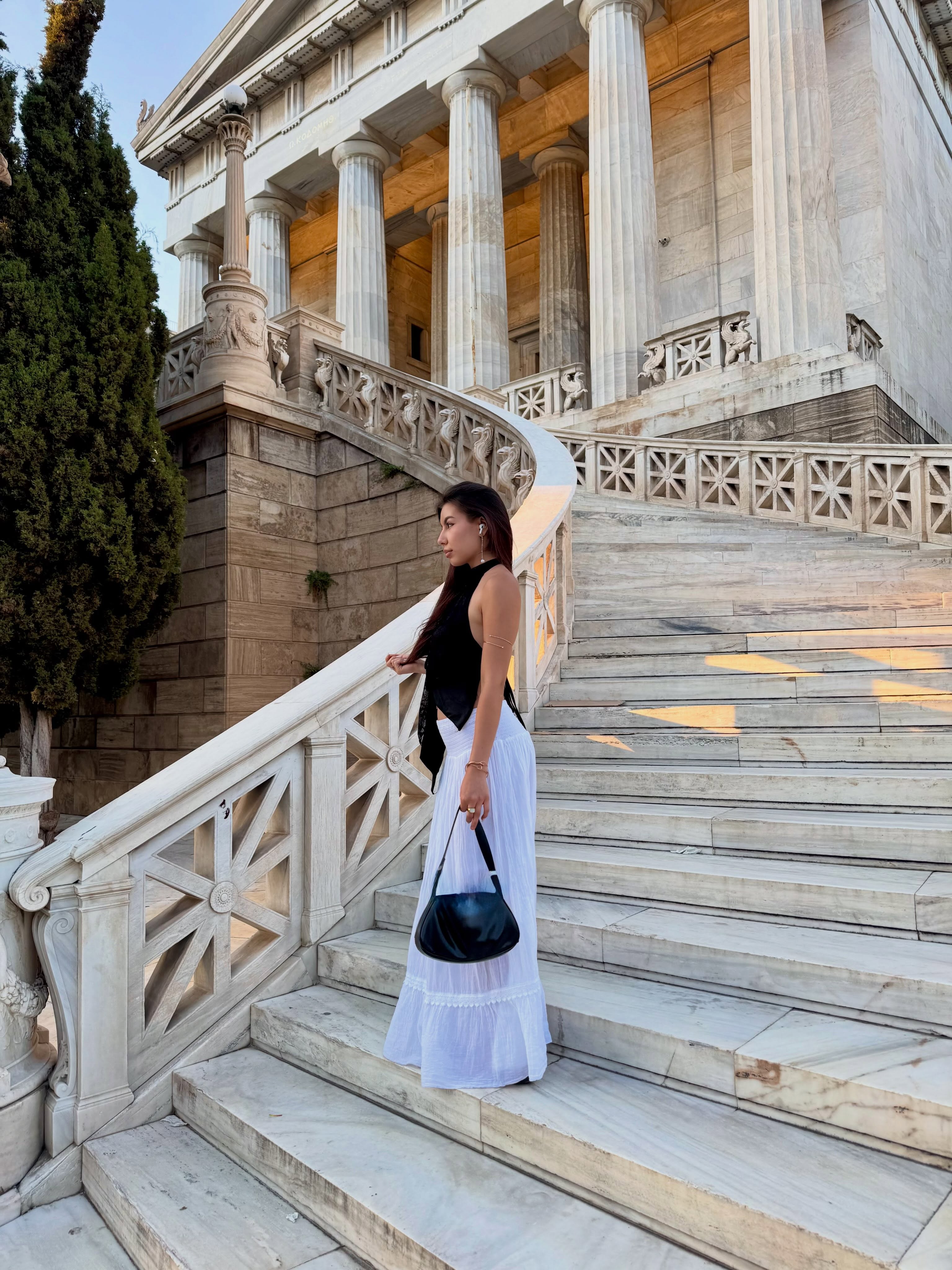 deniseglows standing on stairs wearing black halter top in marble staircase outside neoclassical building