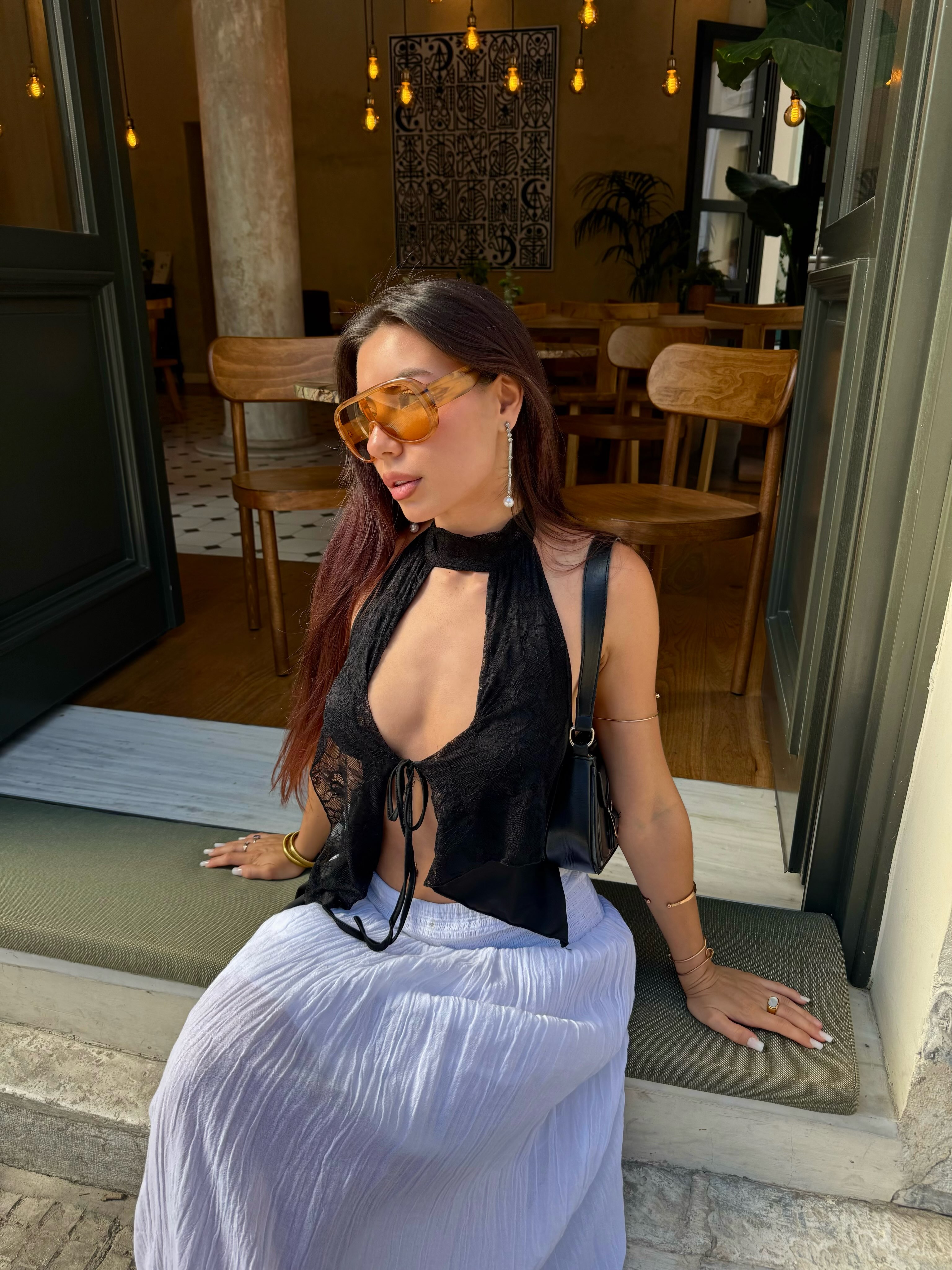 deniseglows sitting on a step wearing black lace halter top in cafe entrance
