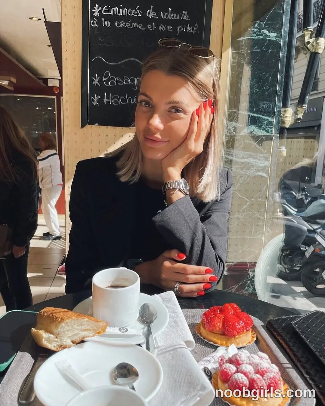 dreamana Sitting at the table with one hand against the side of her face wearing Black long-sleeved jacket in café