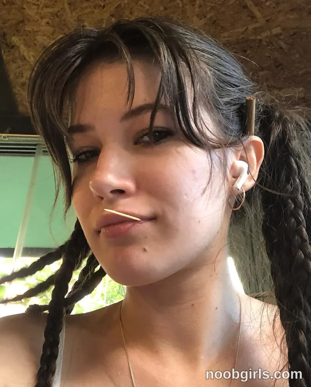 Eff Facing the camera with her head turned slightly wearing White thin-strapped top, partially visible