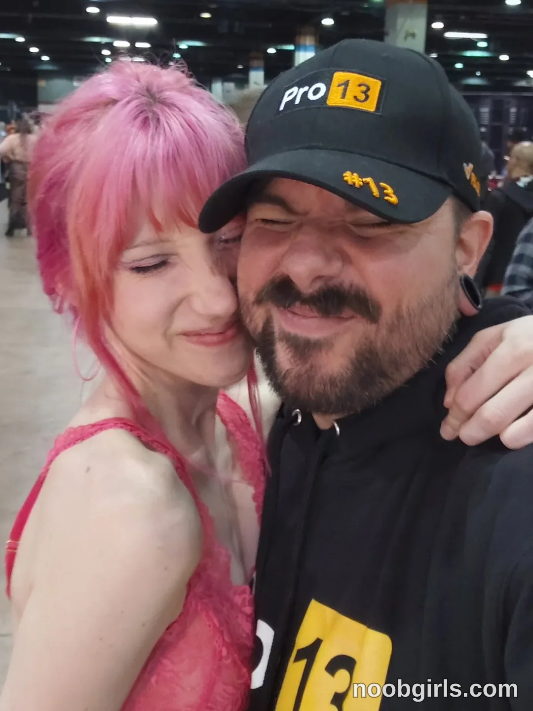 Els hugging wearing pink lace top in convention hall