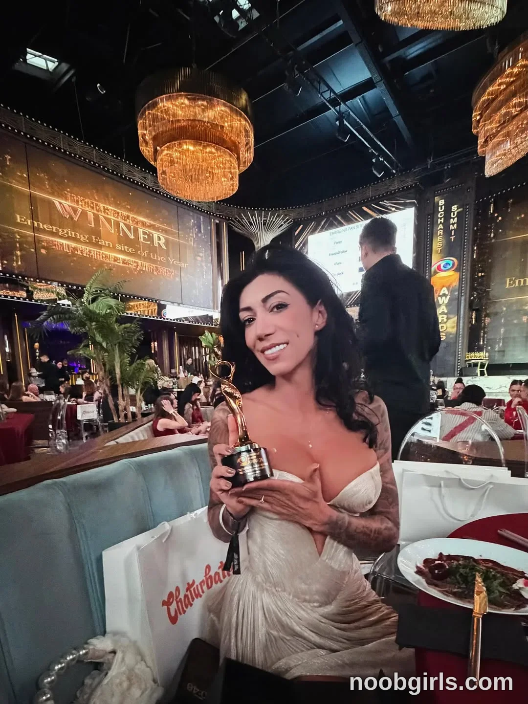 Evelyne seated in a booth wearing ivory strapless dress with a gathered skirt in restaurant