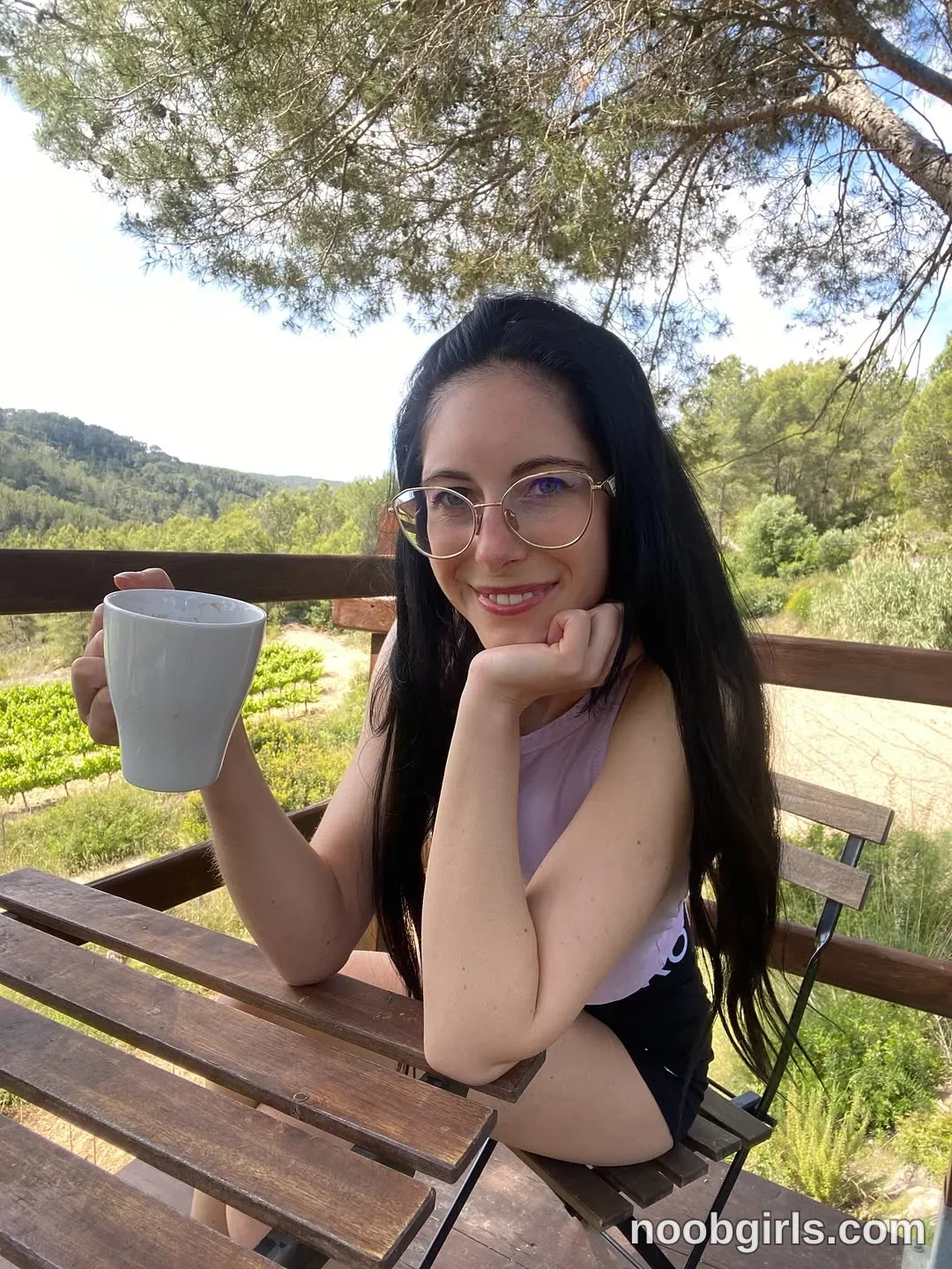 Nikki Gia Sitting on a chair wearing Light purple sleeveless top in wooden deck