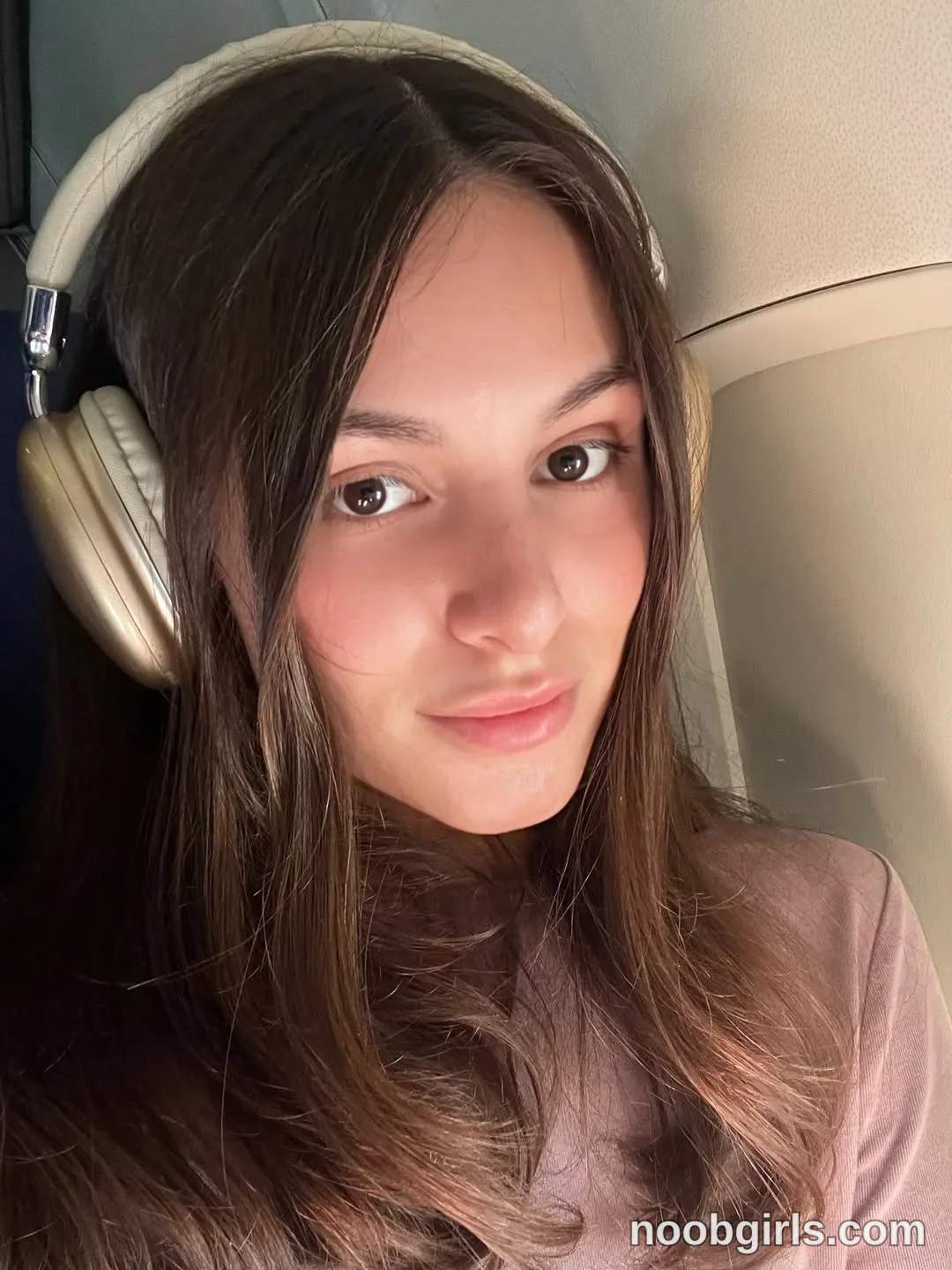 Gracie Smith Sitting with headphones on wearing Muted brown-purple long-sleeved top with a high neckline