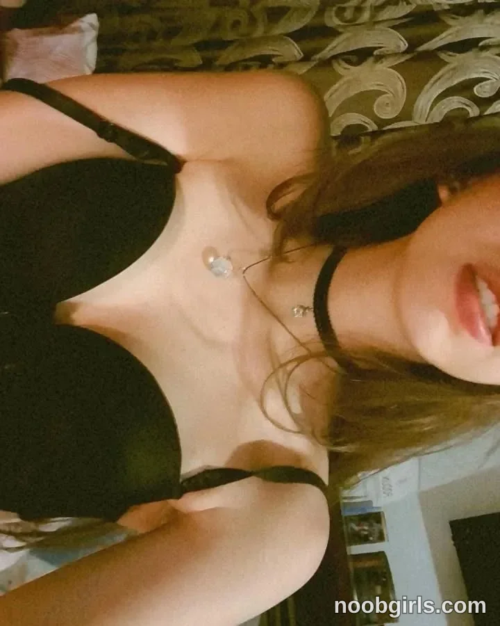 Jelly Reclining against the sofa wearing Black bra with shoulder straps in room
