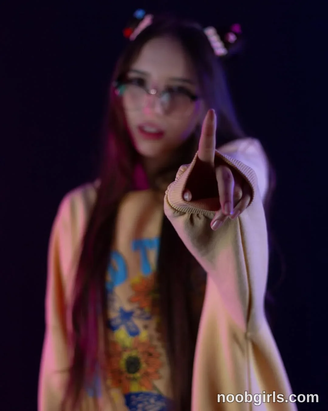 Jelly Facing the camera with one arm extended toward it wearing Light beige open-front cardigan with long sleeves