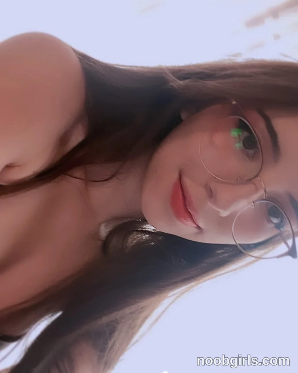 Jelly Facing the camera in a close-up with her head tilted wearing Black top, partially visible