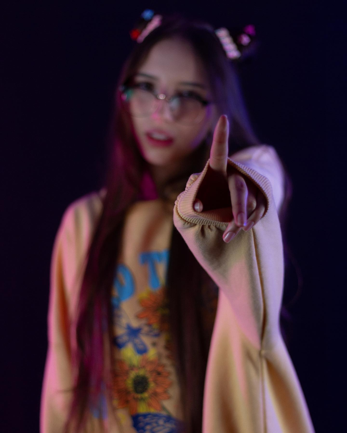 Jelly Facing the camera with one arm extended toward it wearing Light beige open-front cardigan with long sleeves