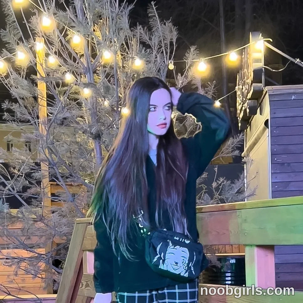 Katana Standing with one arm raised wearing Black long-sleeved top