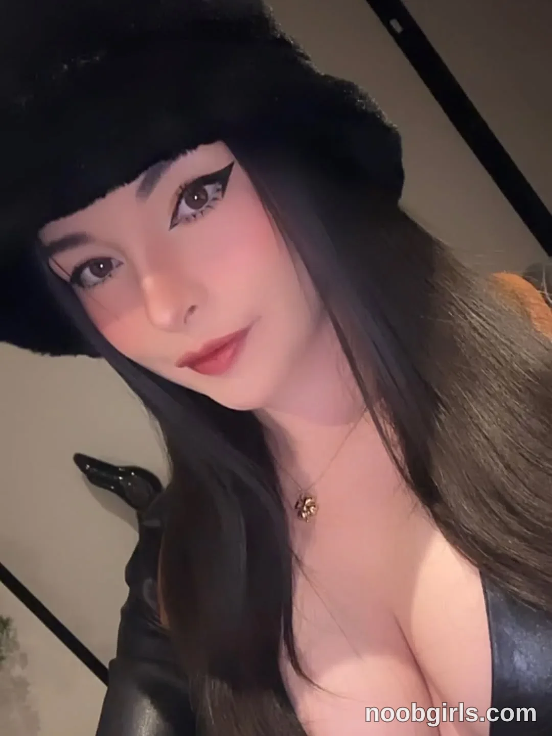 lau__1 facing the camera with her head tilted wearing black fuzzy hat in specific kind of room not identifiable