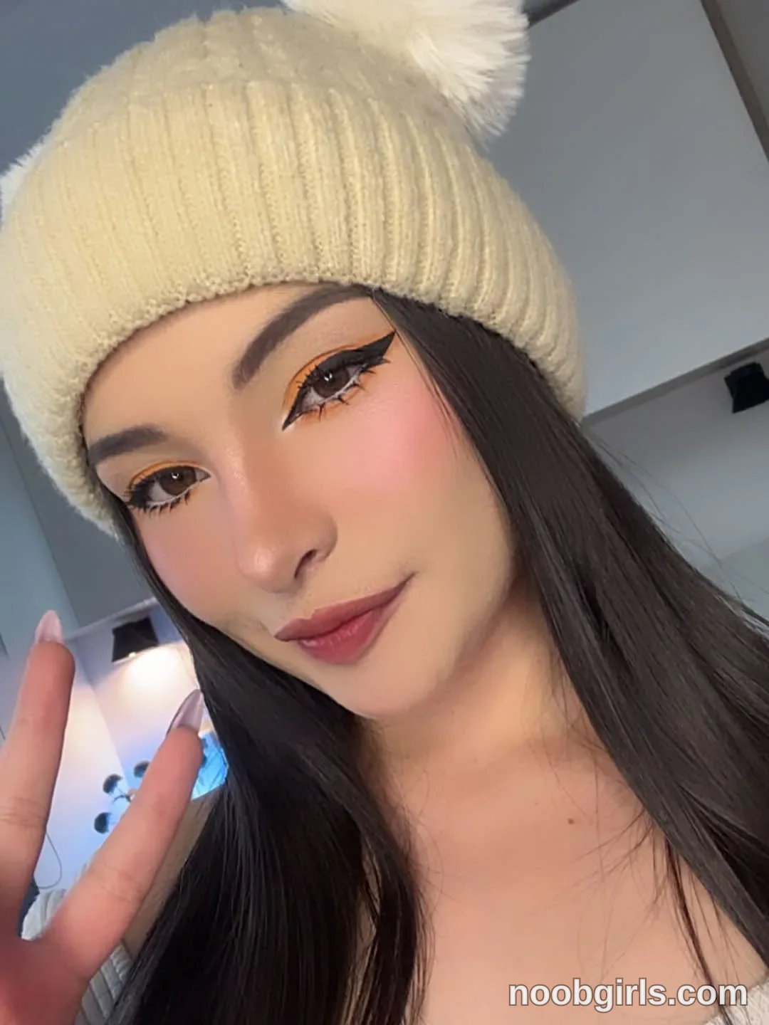 lau__1 Facing the camera wearing Cream ribbed knit hat with a cream pom-pom in a room