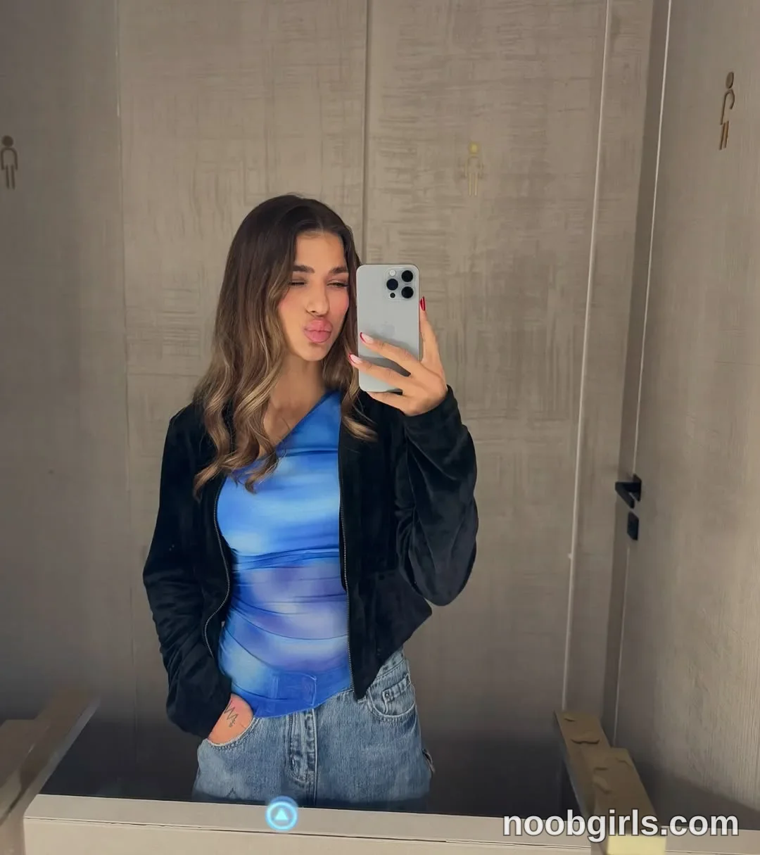 LennaGoddess Holding a smartphone toward the mirror with one hand wearing Black zip-front jacket in restroom