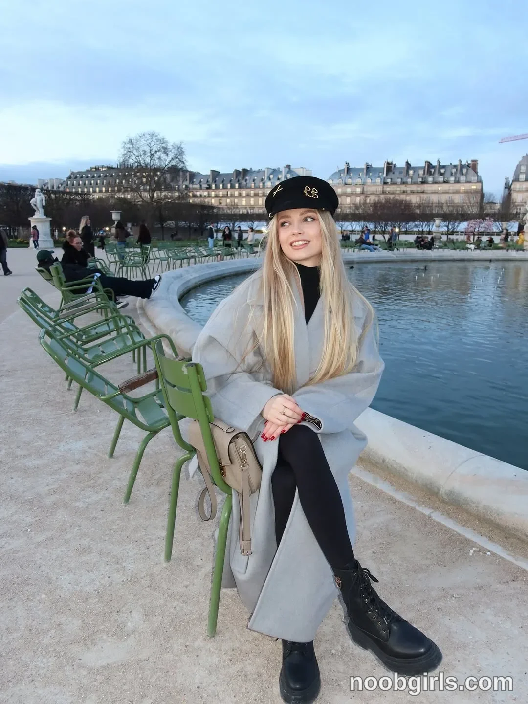Nastya Sitting on a chair with her legs crossed wearing Black beret with gold-coloured lettering