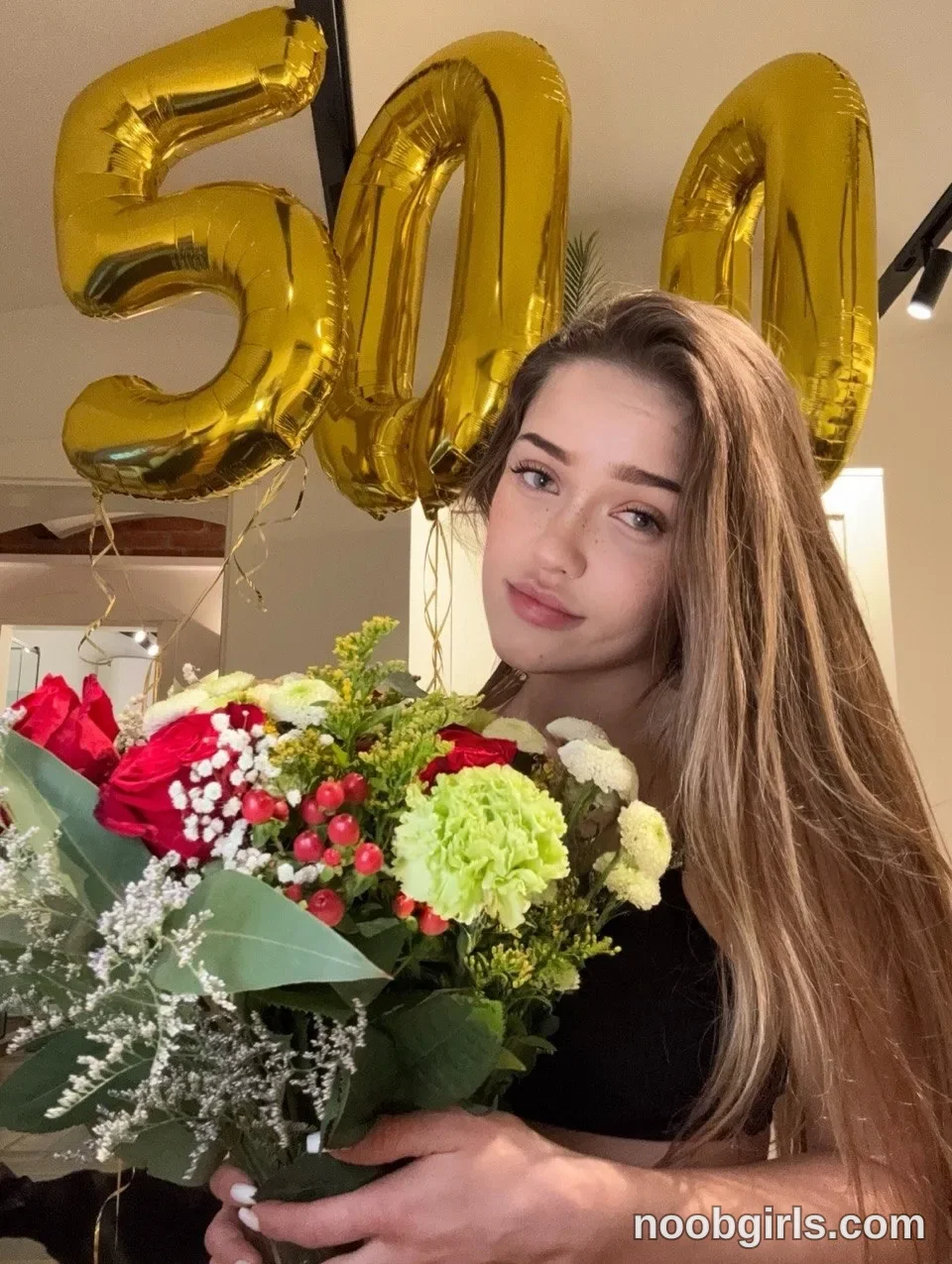 mode_bad holding a flower bouquet in front of herself wearing black top in room