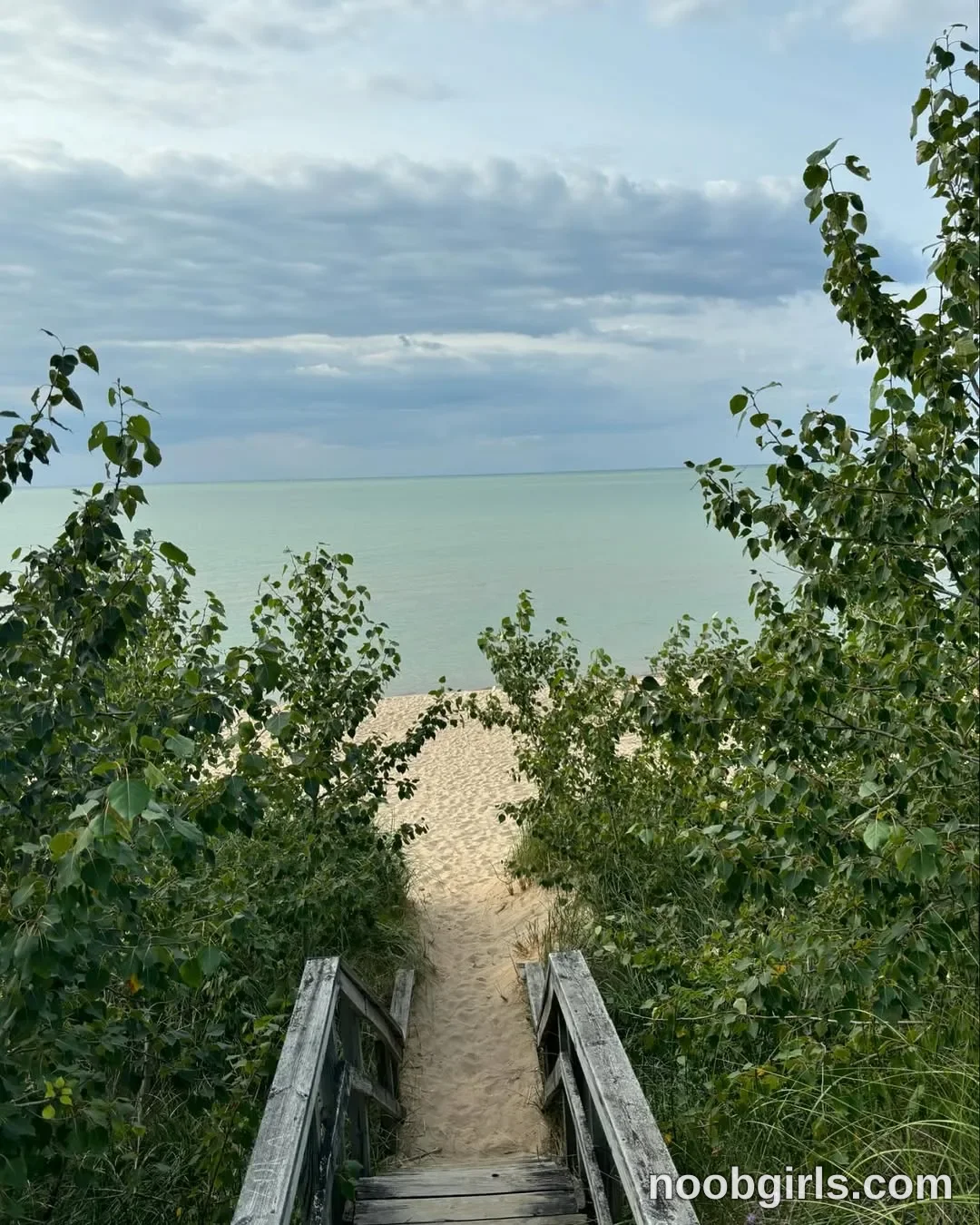 Mia No person is visible. in wooden steps leading down a sandy path to a beach beside a body of water