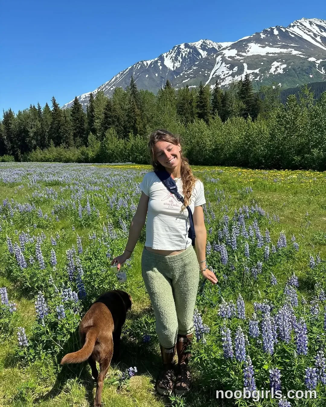 Mia Standing with her head tilted wearing White short-sleeved cropped T-shirt in meadow in Alaska Range