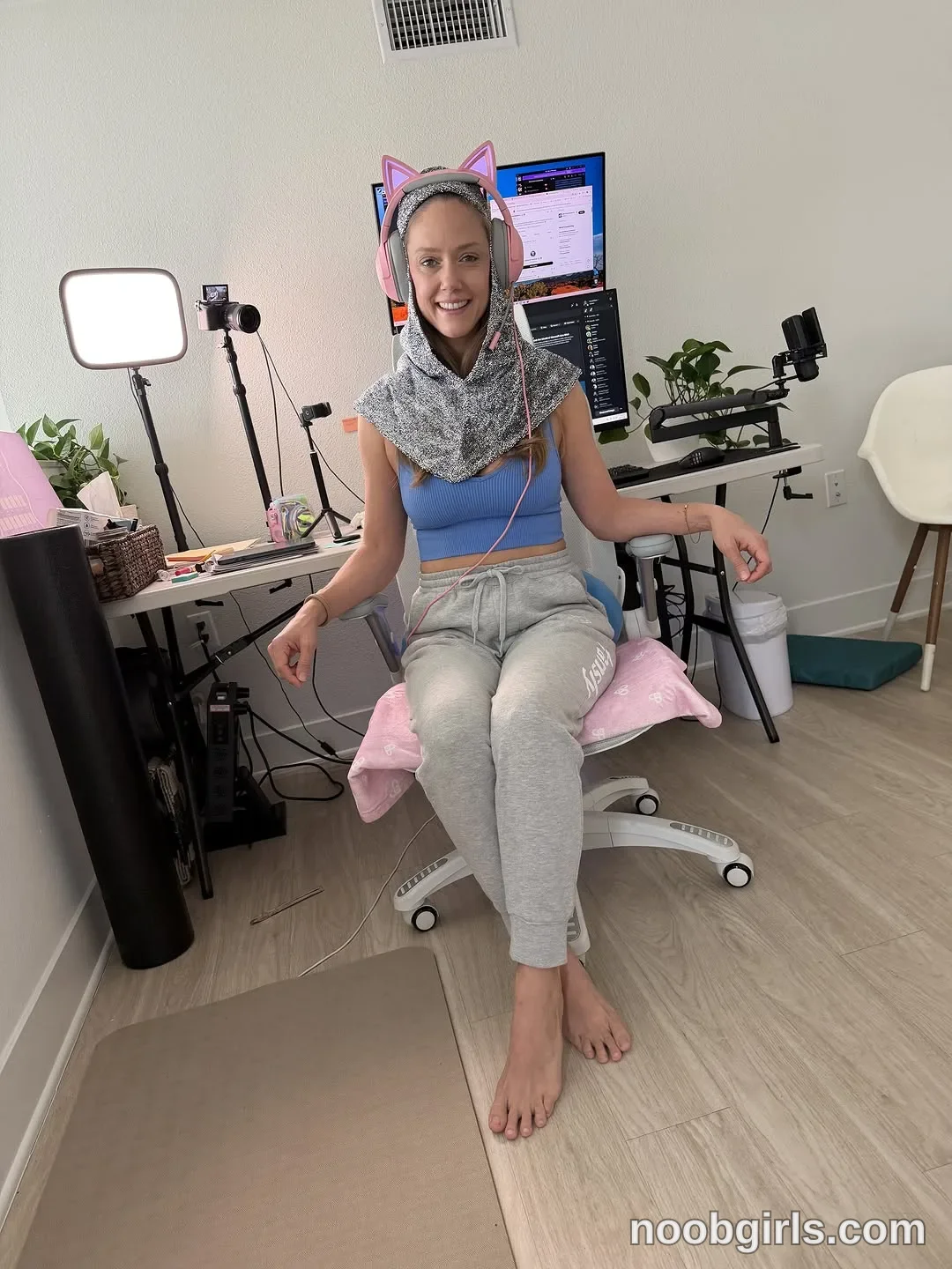 Naked Bakers sitting barefoot on an office chair wearing blue cropped sleeveless top in room