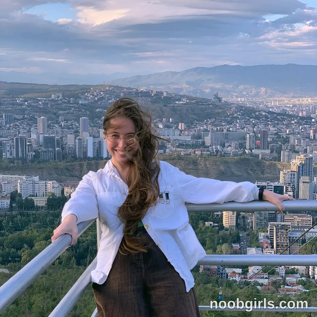 Riley Standing with both arms extended wearing White long-sleeved button-up shirt worn open