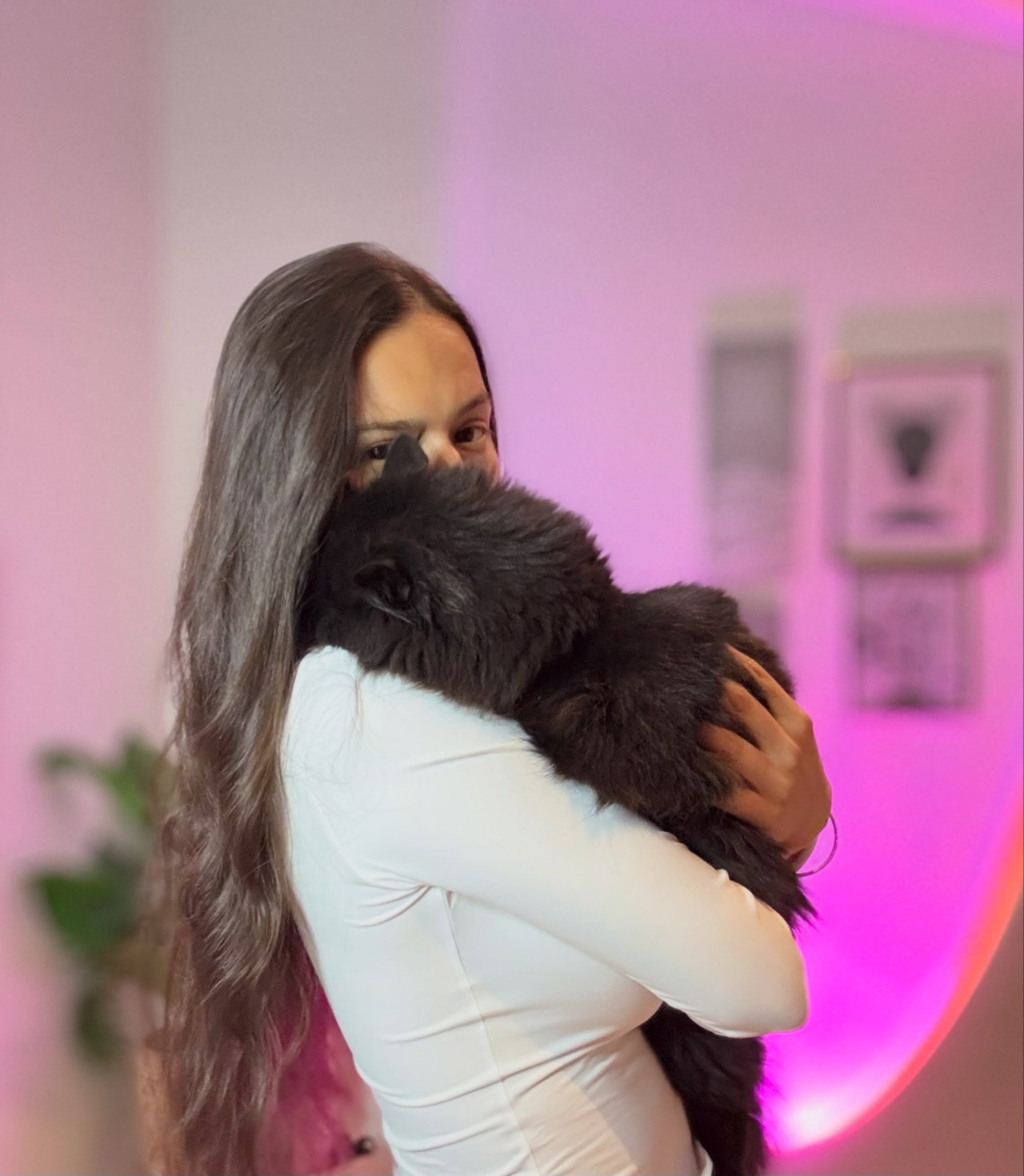 ohanna holding a black cat against her chest wearing white long-sleeved top in room