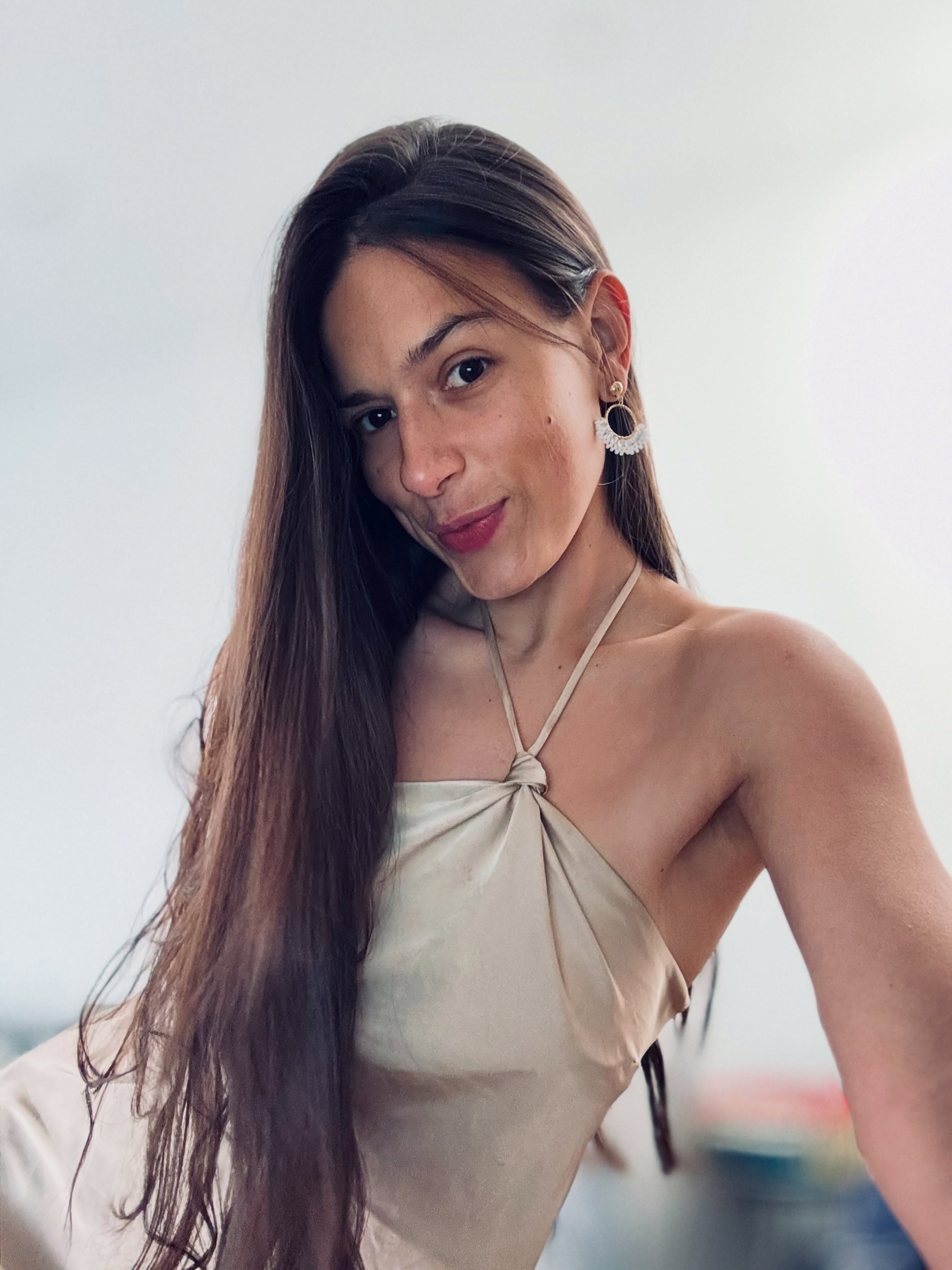 ohanna leaning forward towards the camera with head slightly tilted wearing champagne-beige satin halter-neck top or dress