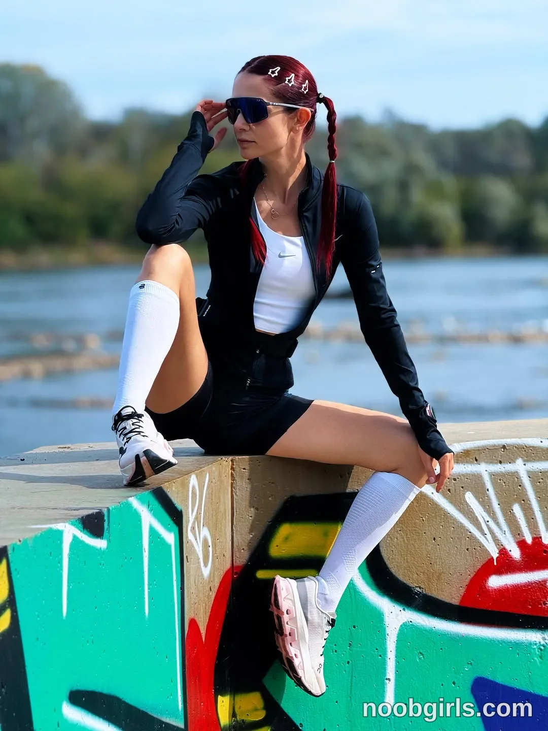 evaoopsy Sitting on the edge of the concrete structure with one knee raised wearing Black long-sleeved zip-front jacket