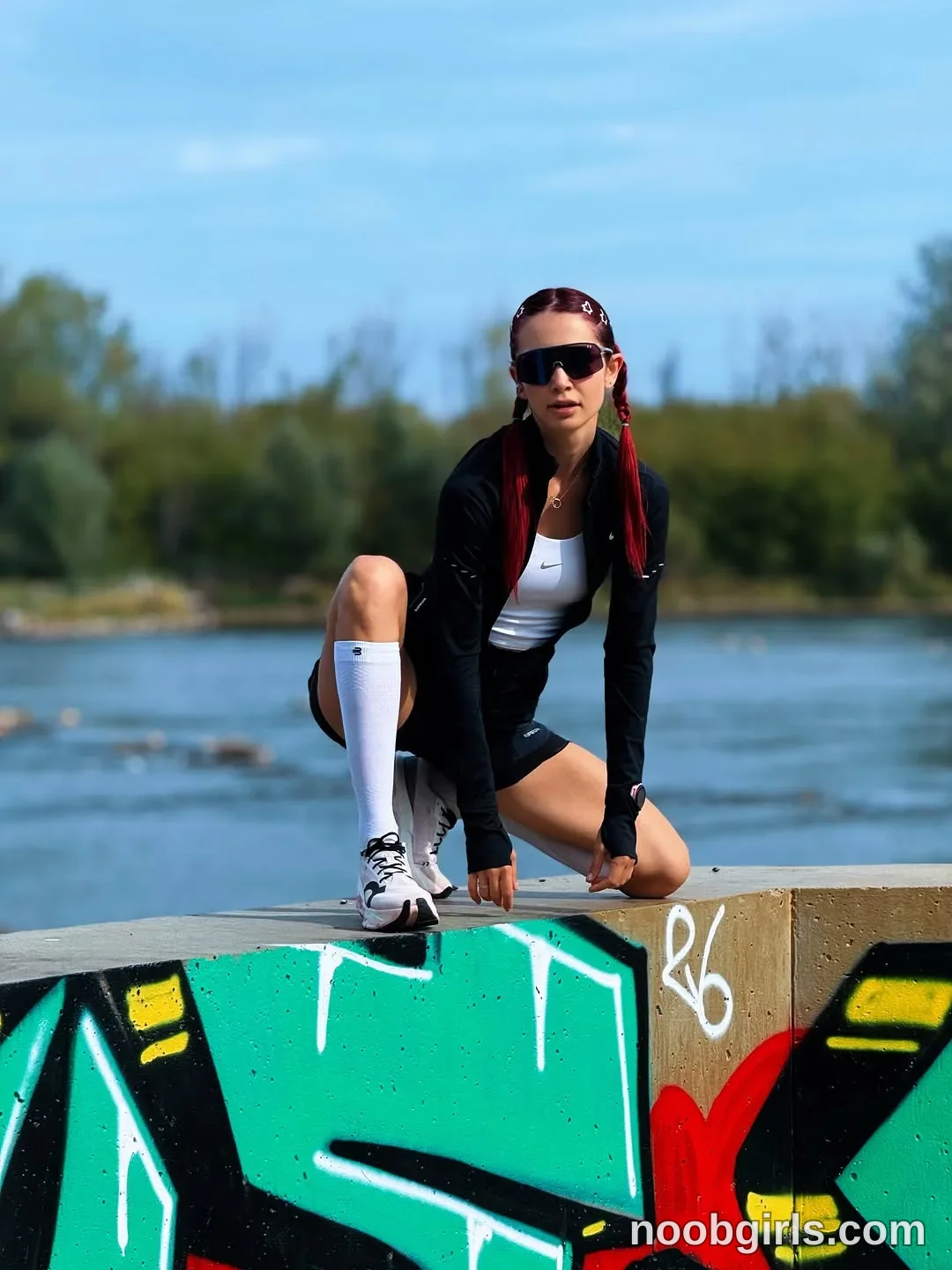 evaoopsy Crouching on top of the concrete wall with one knee raised wearing Black sunglasses