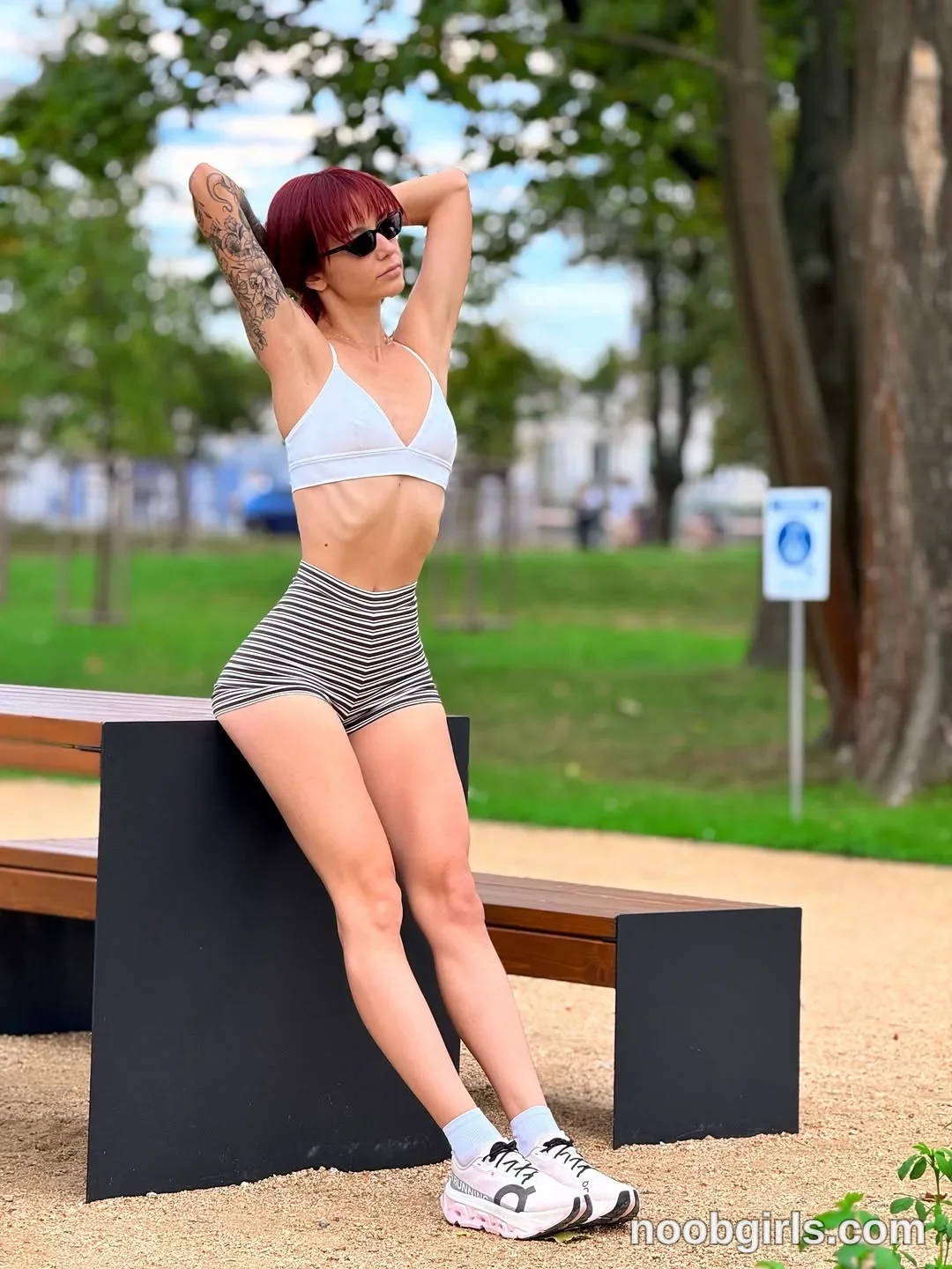evaoopsy Leaning against a bench support with both arms raised wearing White thin-strapped crop top in park
