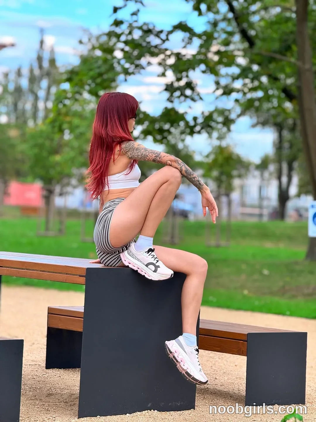evaoopsy Sitting sideways on a bench support with one knee raised wearing White cropped sleeveless top in park